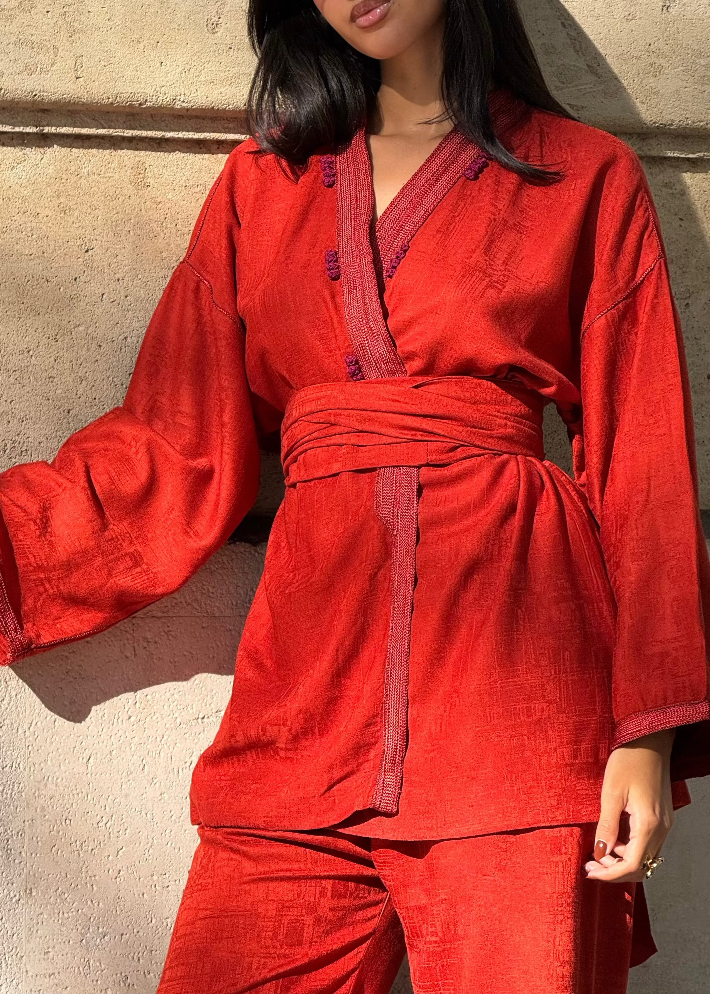 تفاصيل الأزرار باللون العنابي والتشطيبات المصنوعة يدوياً على كيمونو مليفا الحريري الأحمر