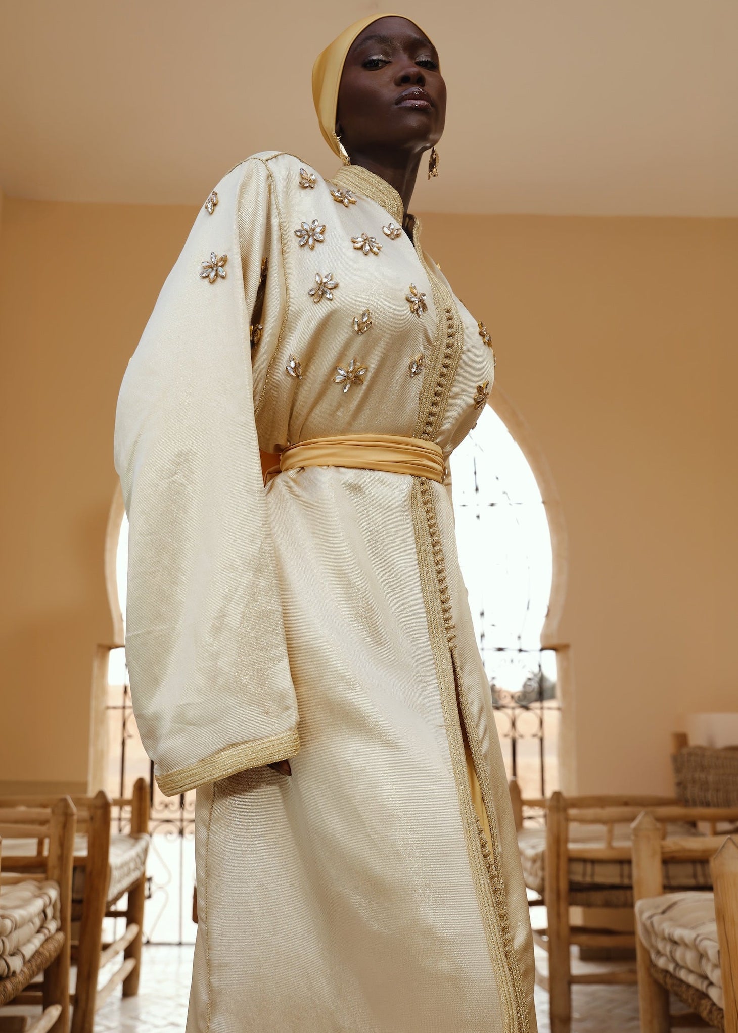 Caftan en soie lamée dorée porté en mouvement, tissu fluide et lumineux.