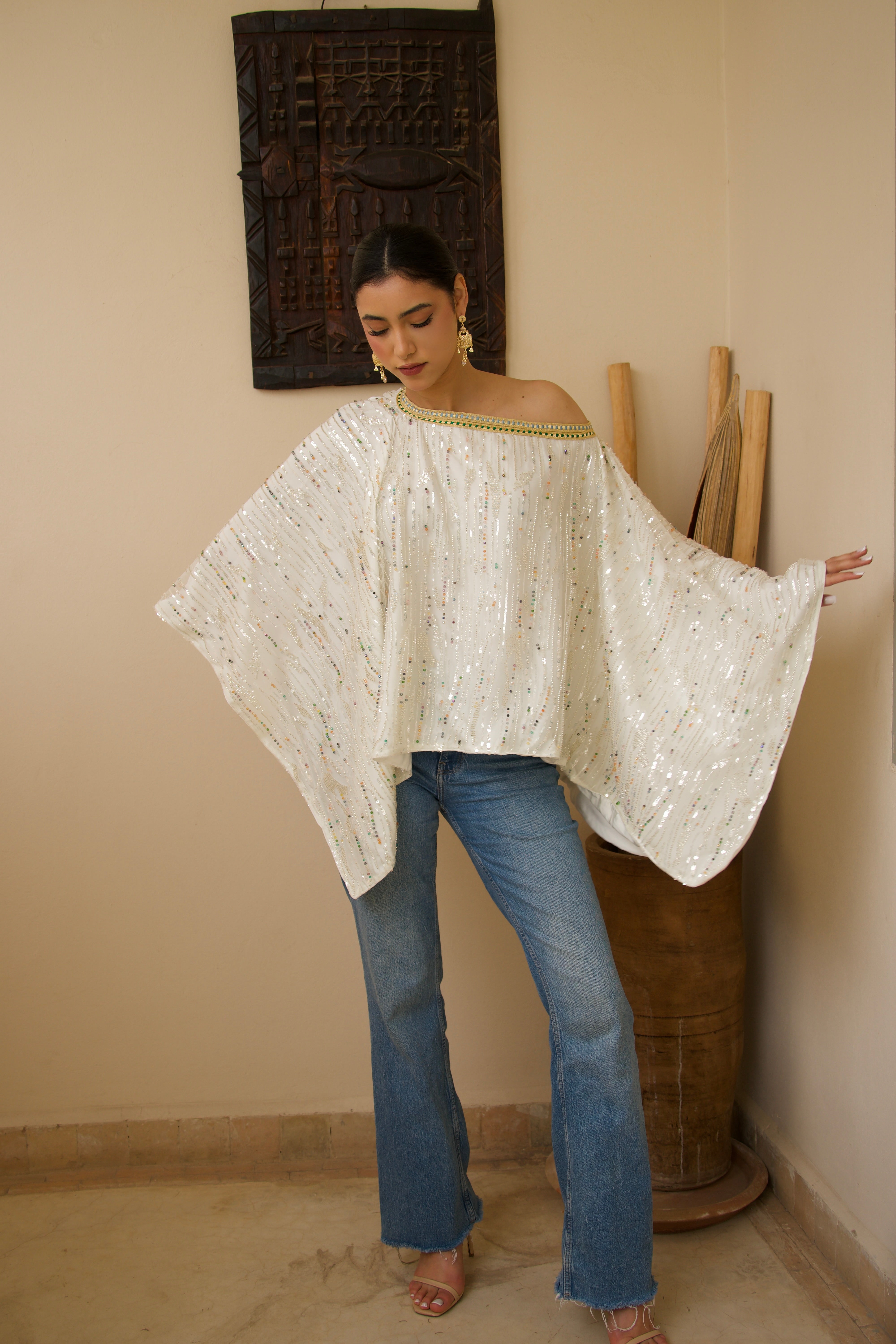 Lightweight white tulle cape with pearl detailing, worn in motion for an airy, flowing effect.
