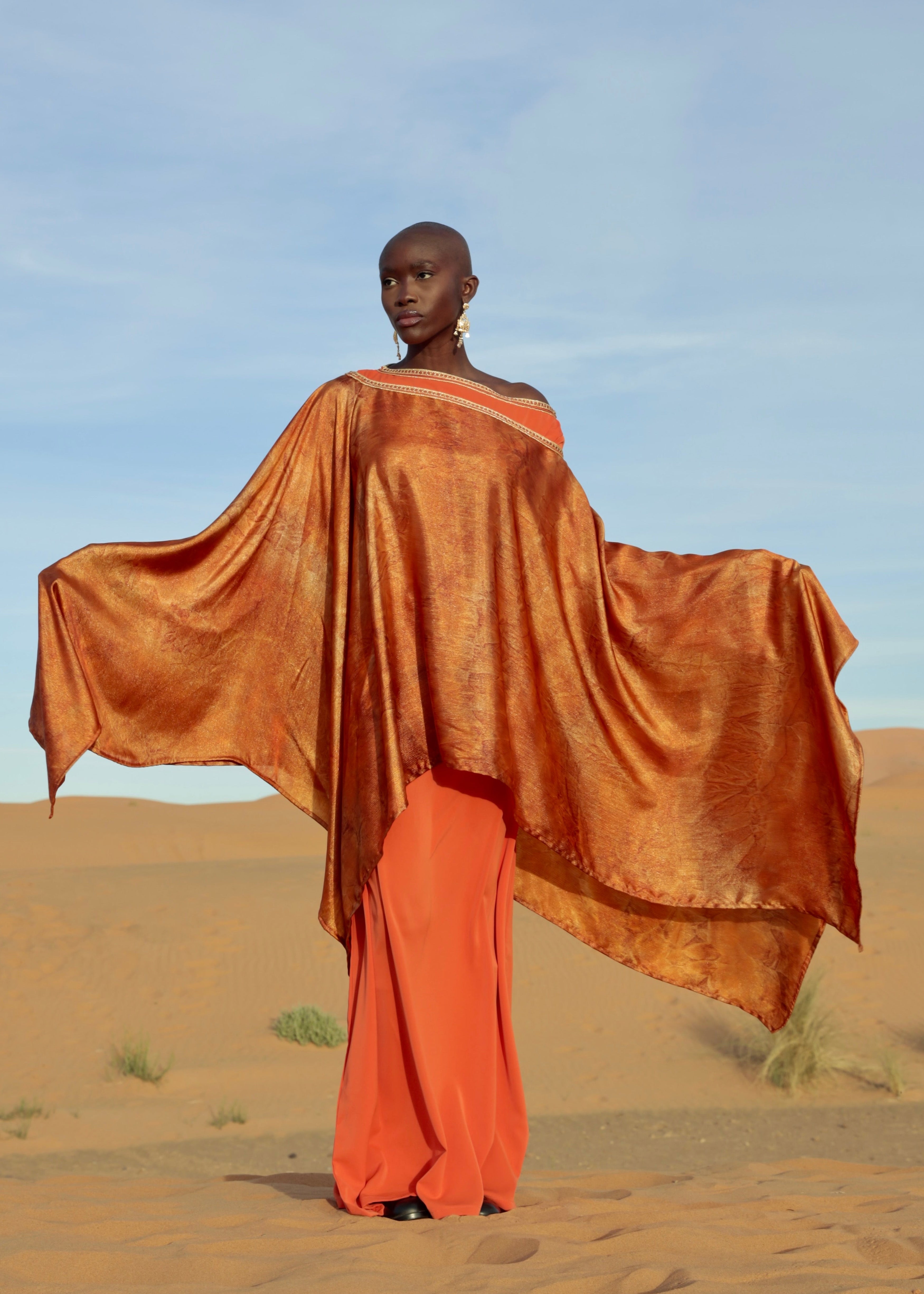 An orange cape printed on flowing lamé silk, highlighting the fabric's lightness and shimmer.