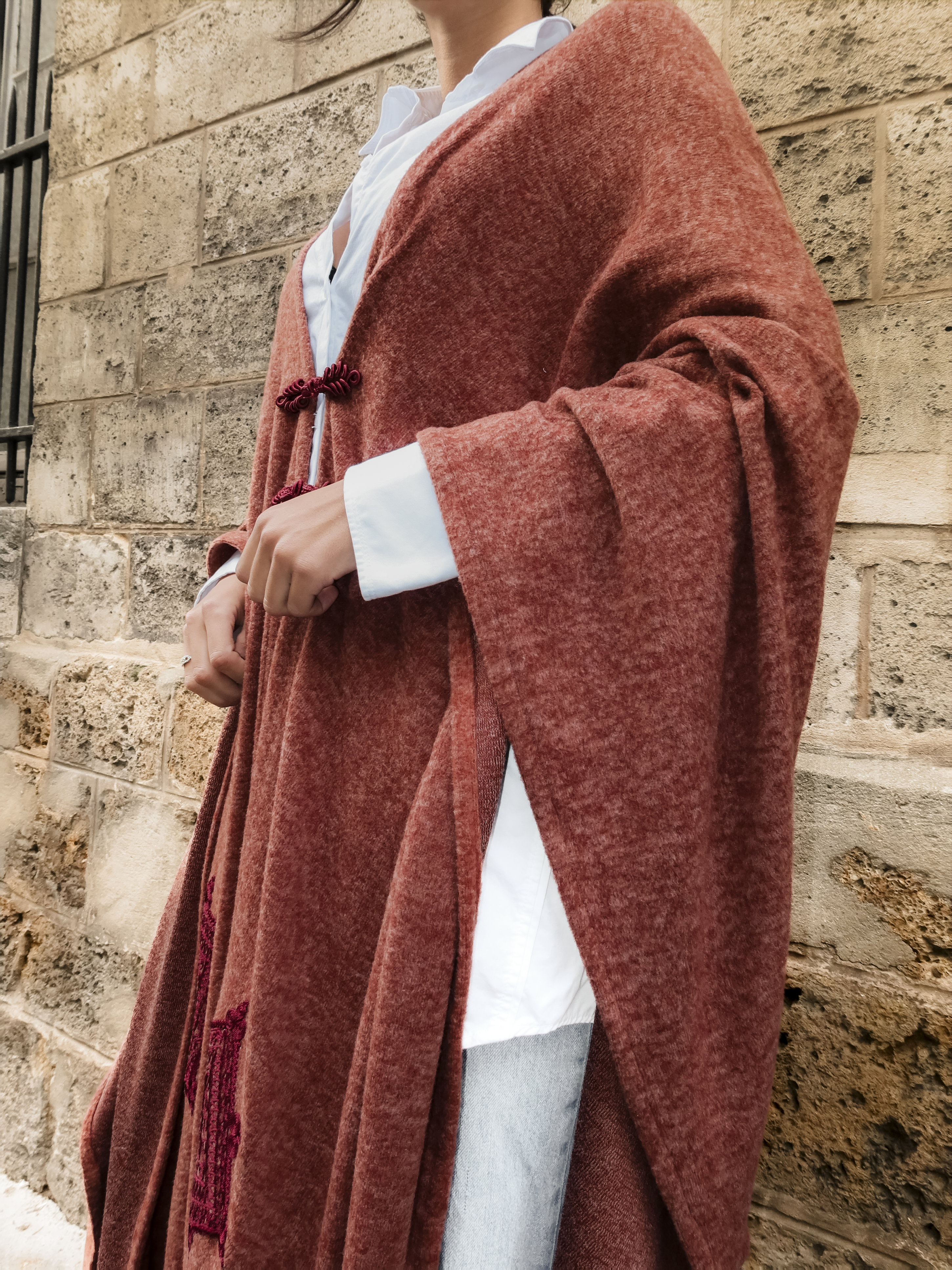 Détail des broderies orientales et des boutons marocains sur gilet bohème long en laine bordeaux