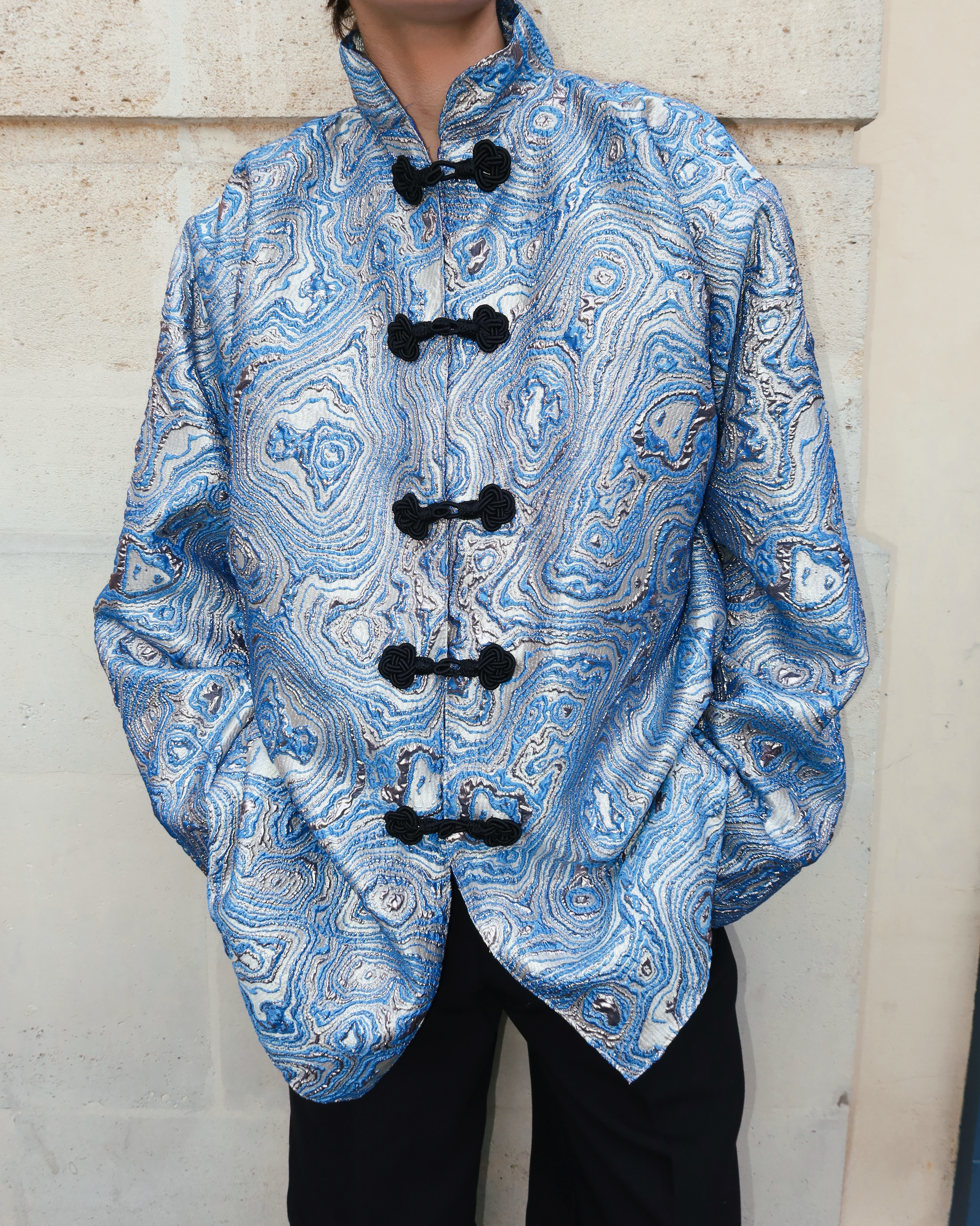 Gros plan sur les crochets marocains noirs artisanaux d’une veste en brocard bleu