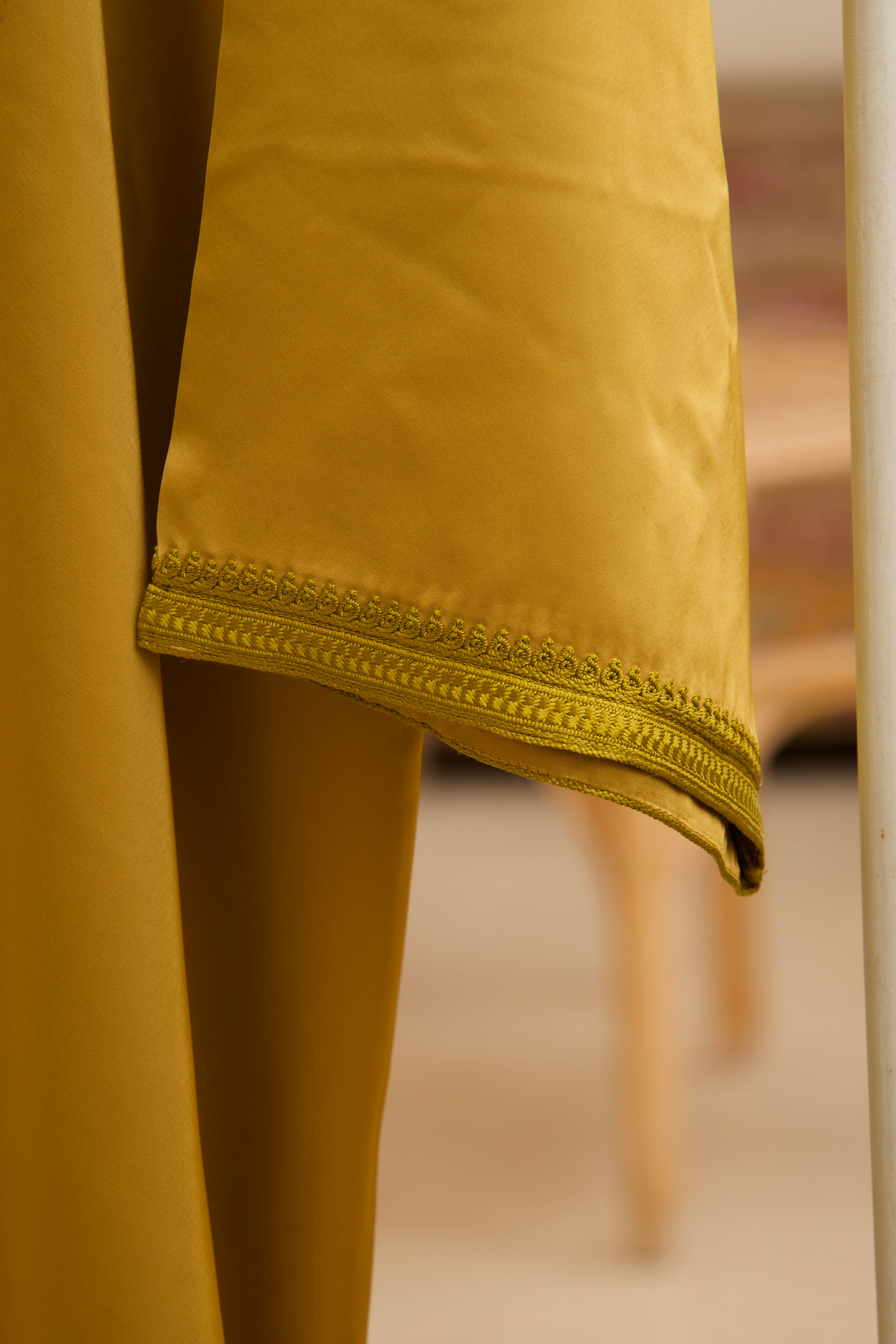 Détail de la manche en satin duchesse moutarde avec finitions soignées.