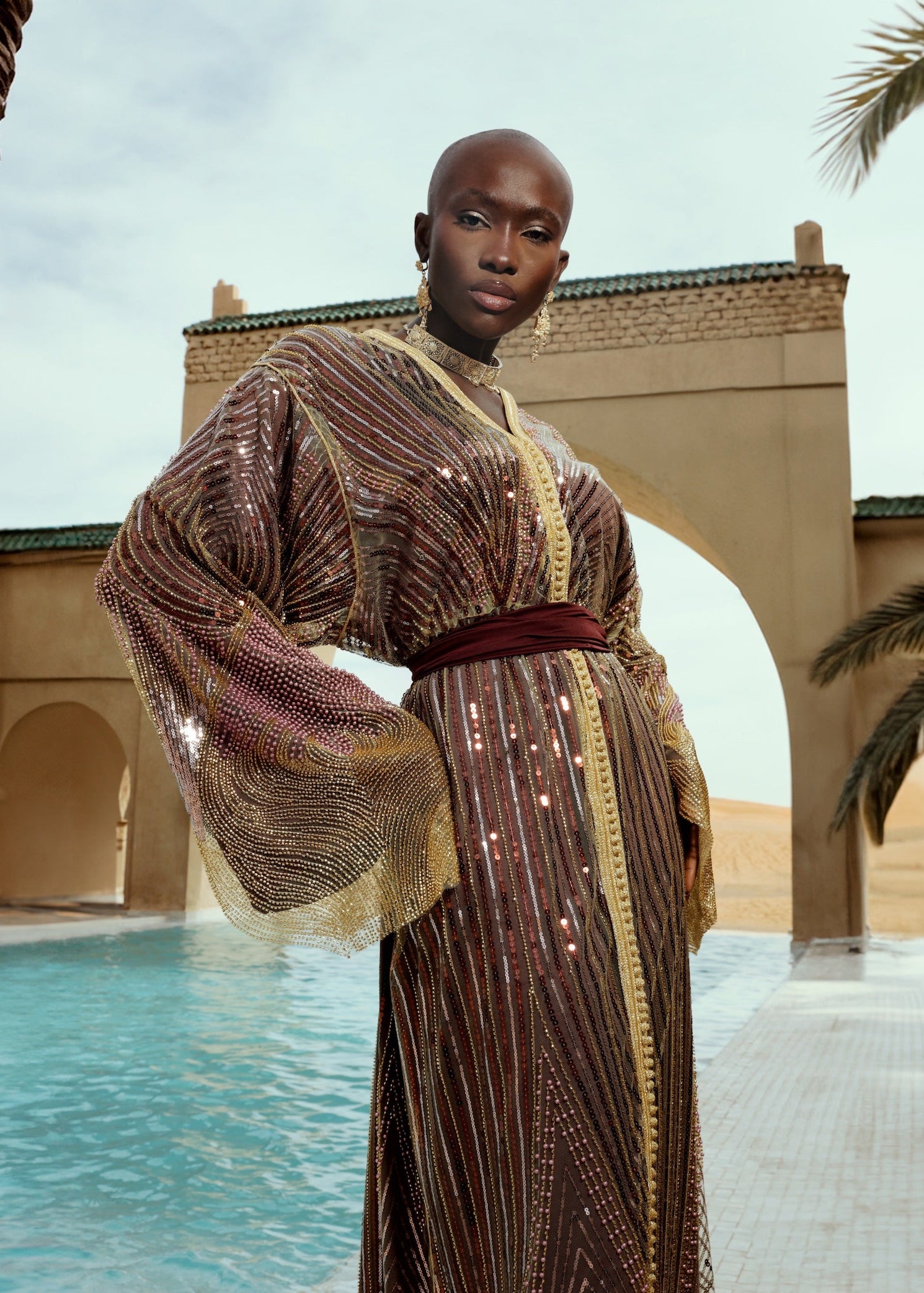 Gros plan sur la sfifa artisanale d’un caftan en tulle perlé doré et bordeaux.