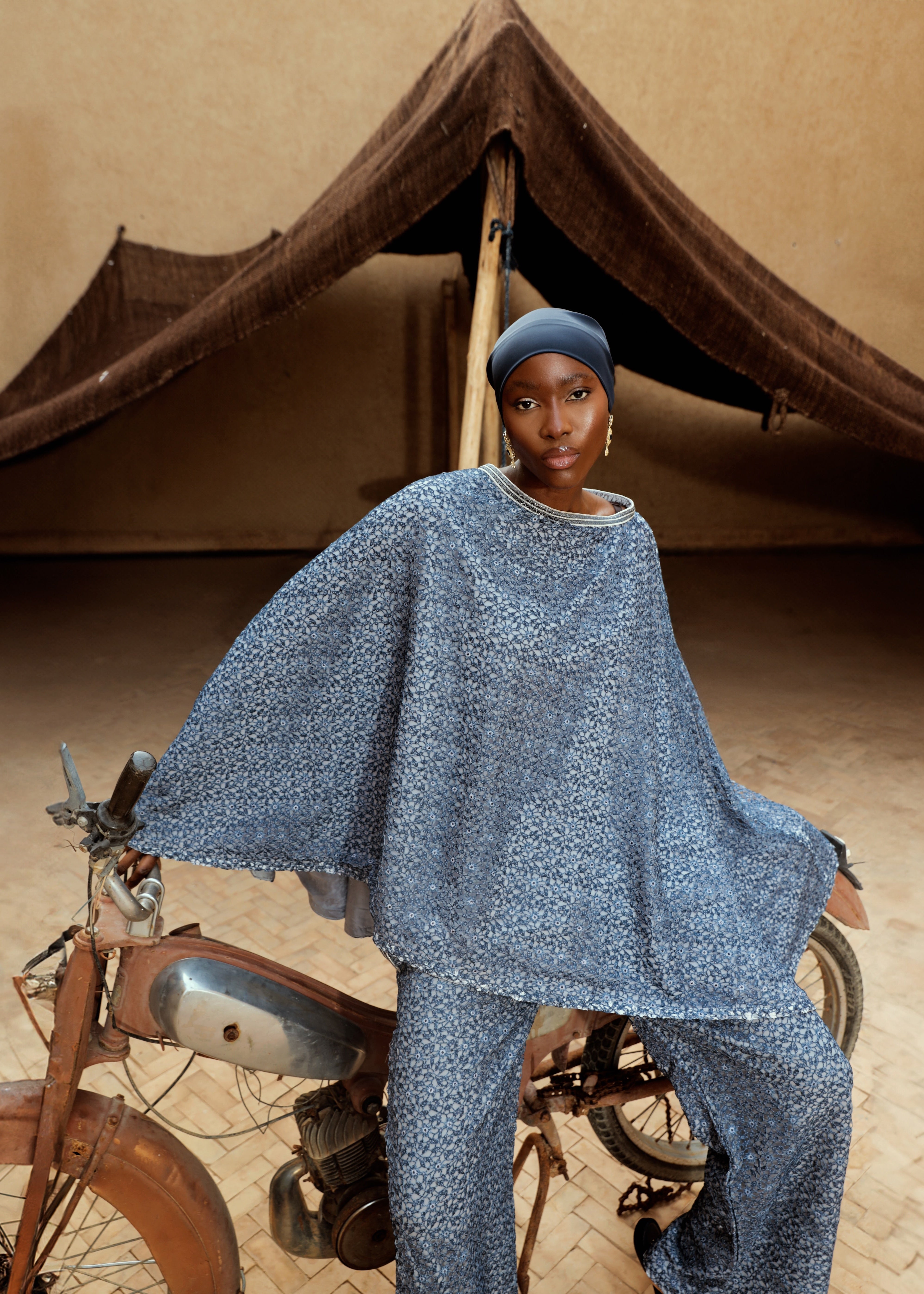 A close-up of the elegant blue lace on a cape-and-pants ensemble.