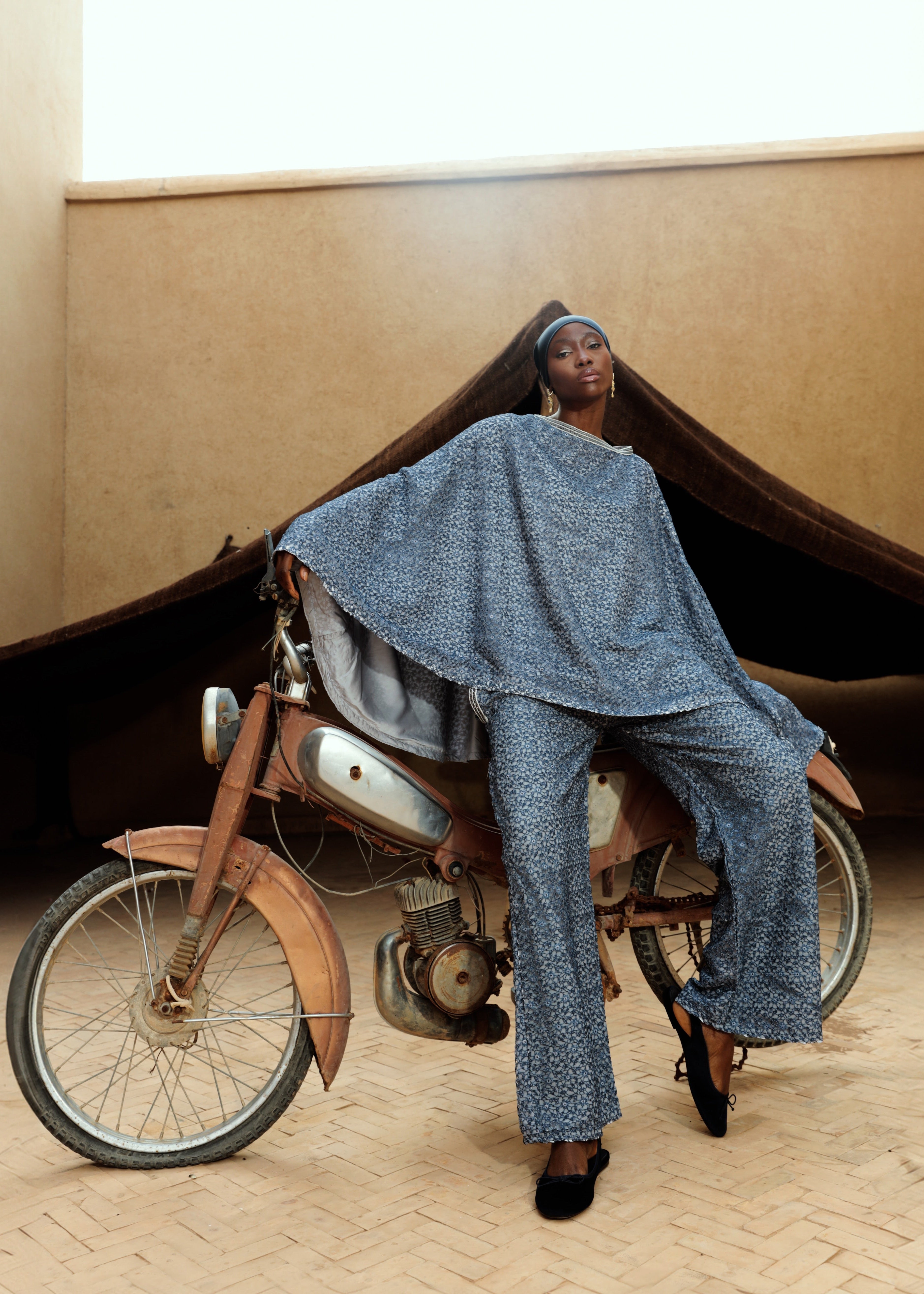 A blue lace cape and pants set worn in motion, creating a flowing and elegant look.