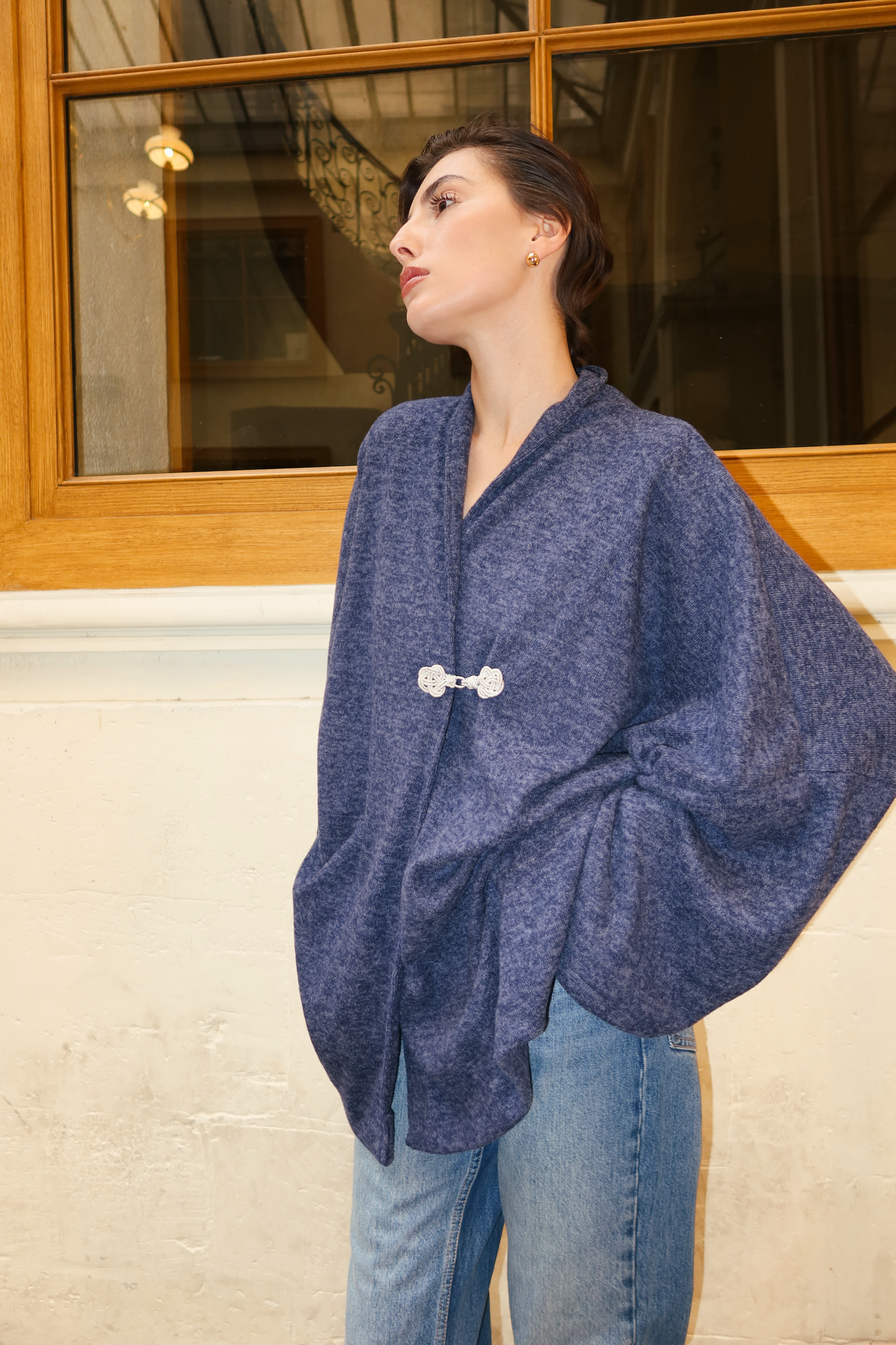 Gilet en laine bleu vu de profil, mettant en valeur une silhouette fluide et un style intemporel