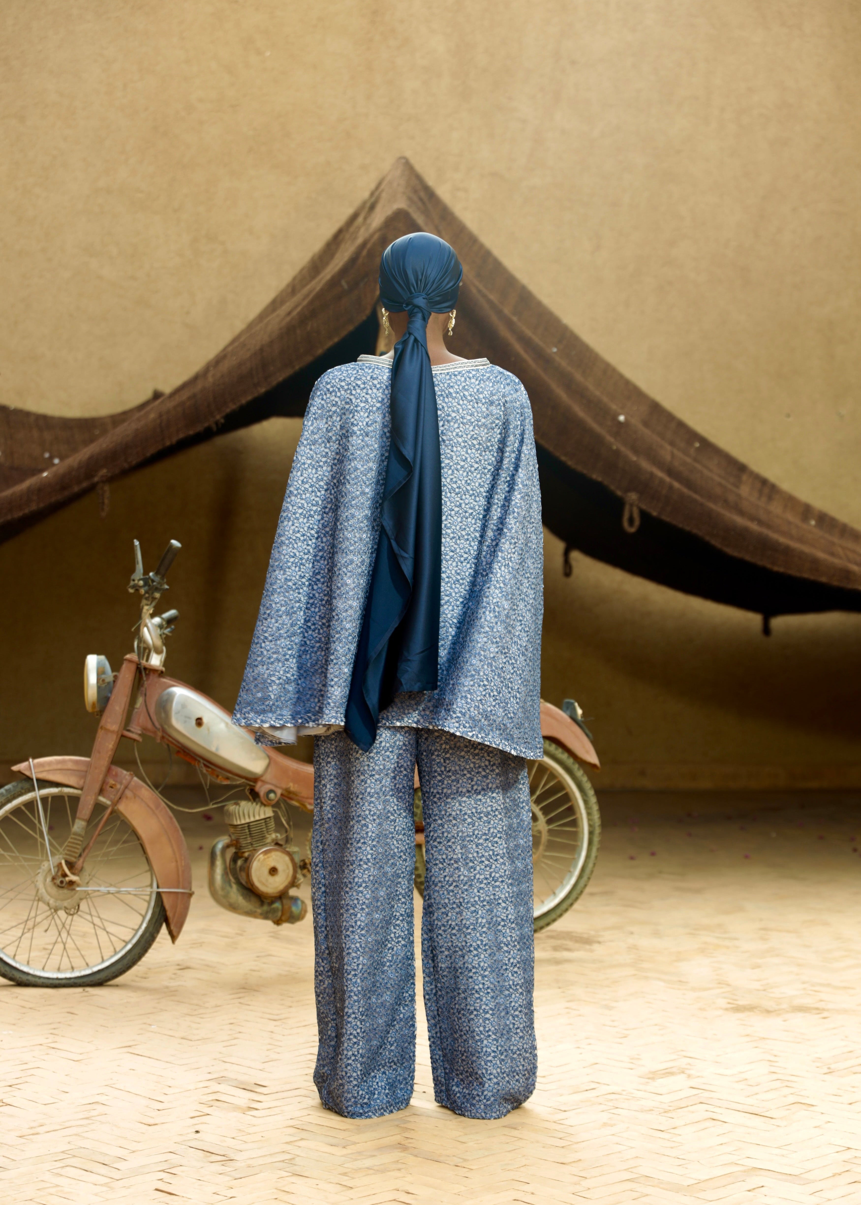 Close-up of the handcrafted sfifa detail on a blue lace cape and pants set.