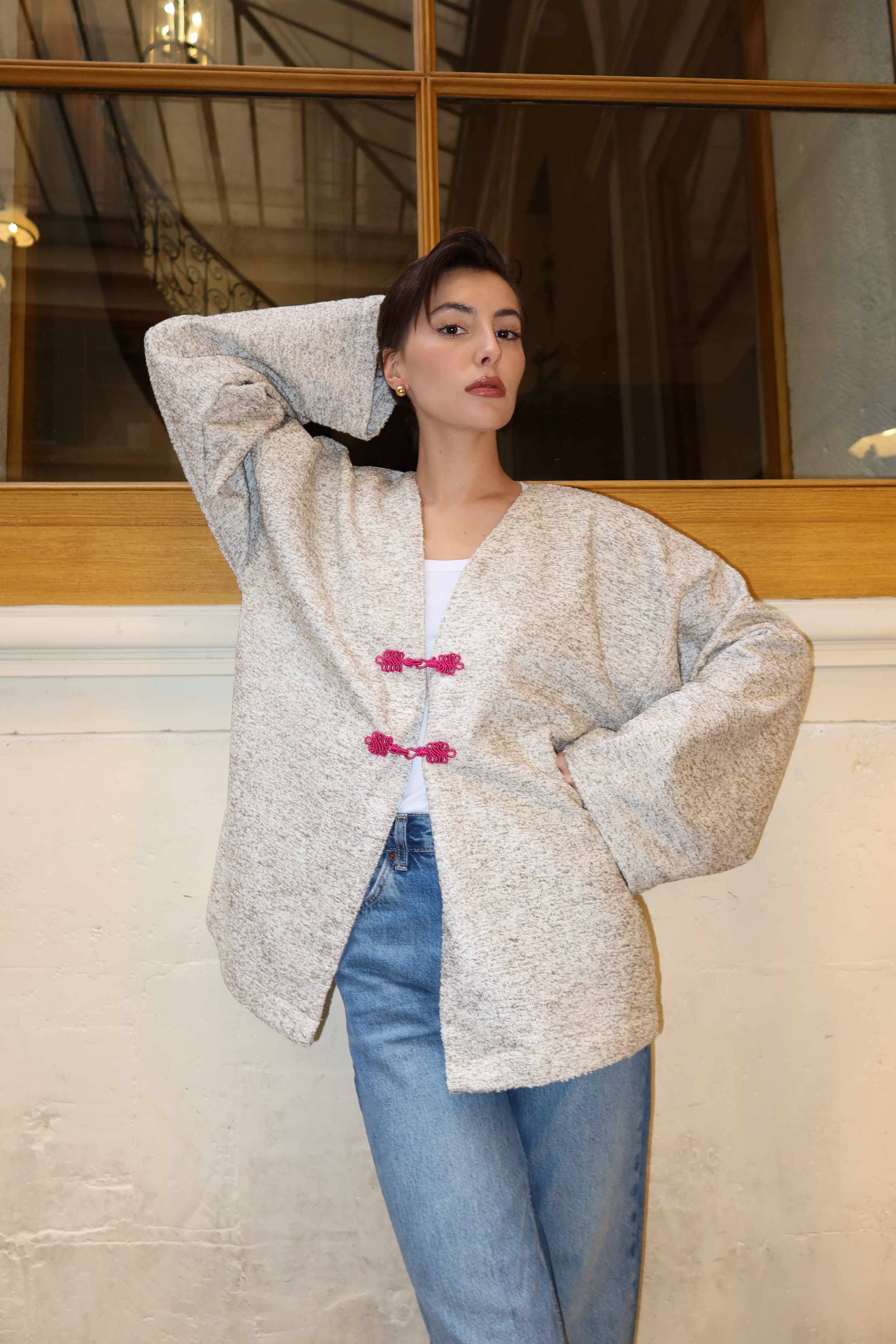 Veste en laine bouclée vert et beige en mouvement révélant une texture bouclée raffinée et des boutons marocains roses