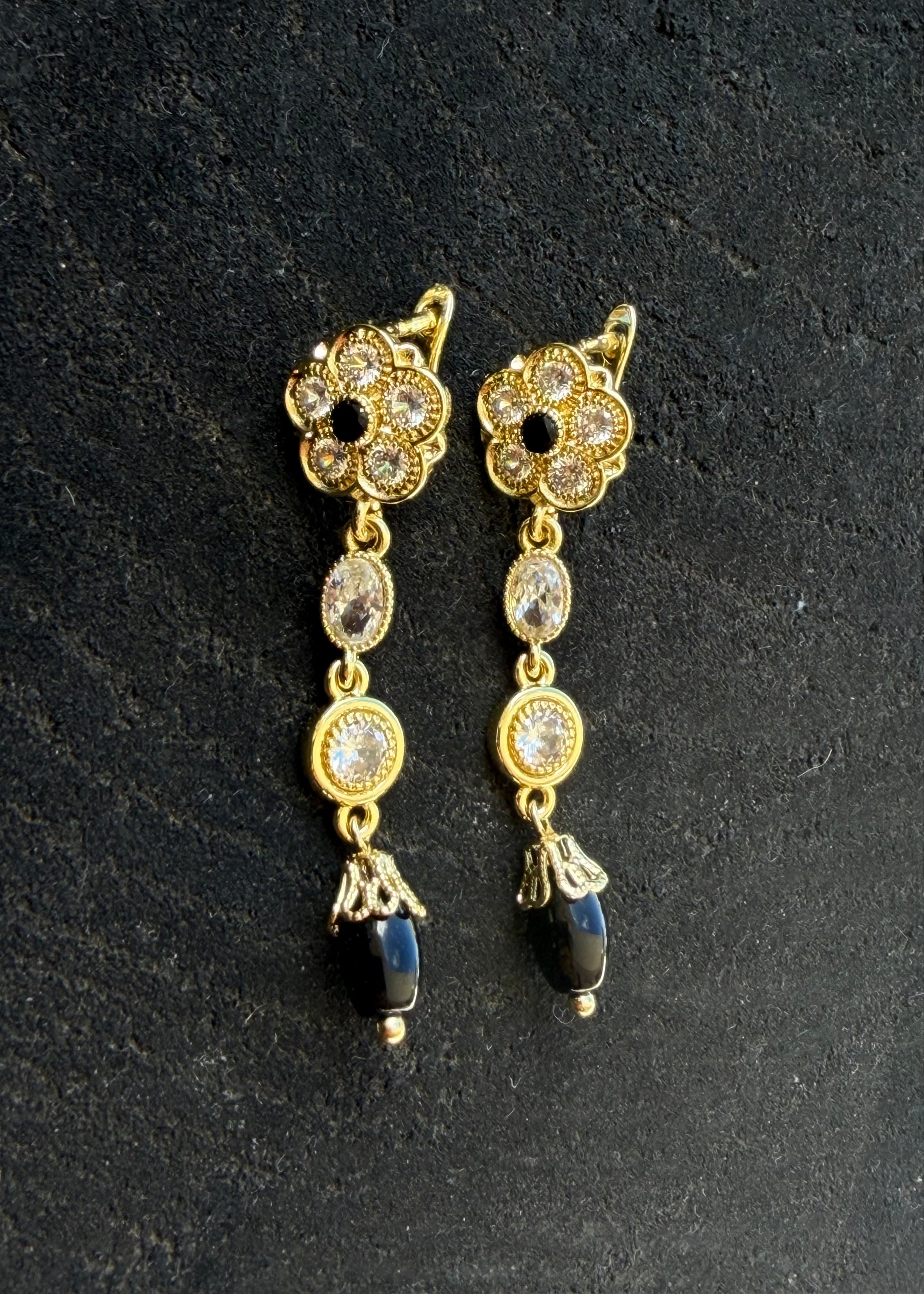 Gold-tone oriental earrings with black teardrop pendants and a rosette of light-colored stones