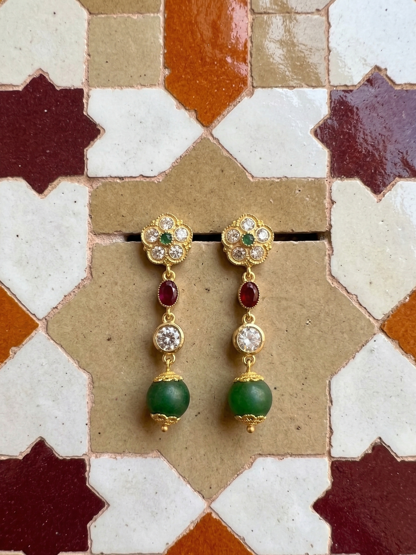 Gold-tone oriental earrings with a green pearl, a rosette of light-colored stones, and touches of red and green