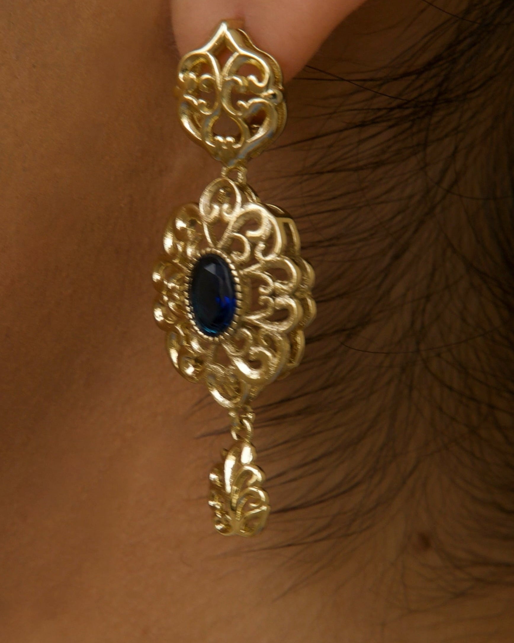 Détail boucles d’oreilles rondes dorées et bleues finition brillante et contraste élégant