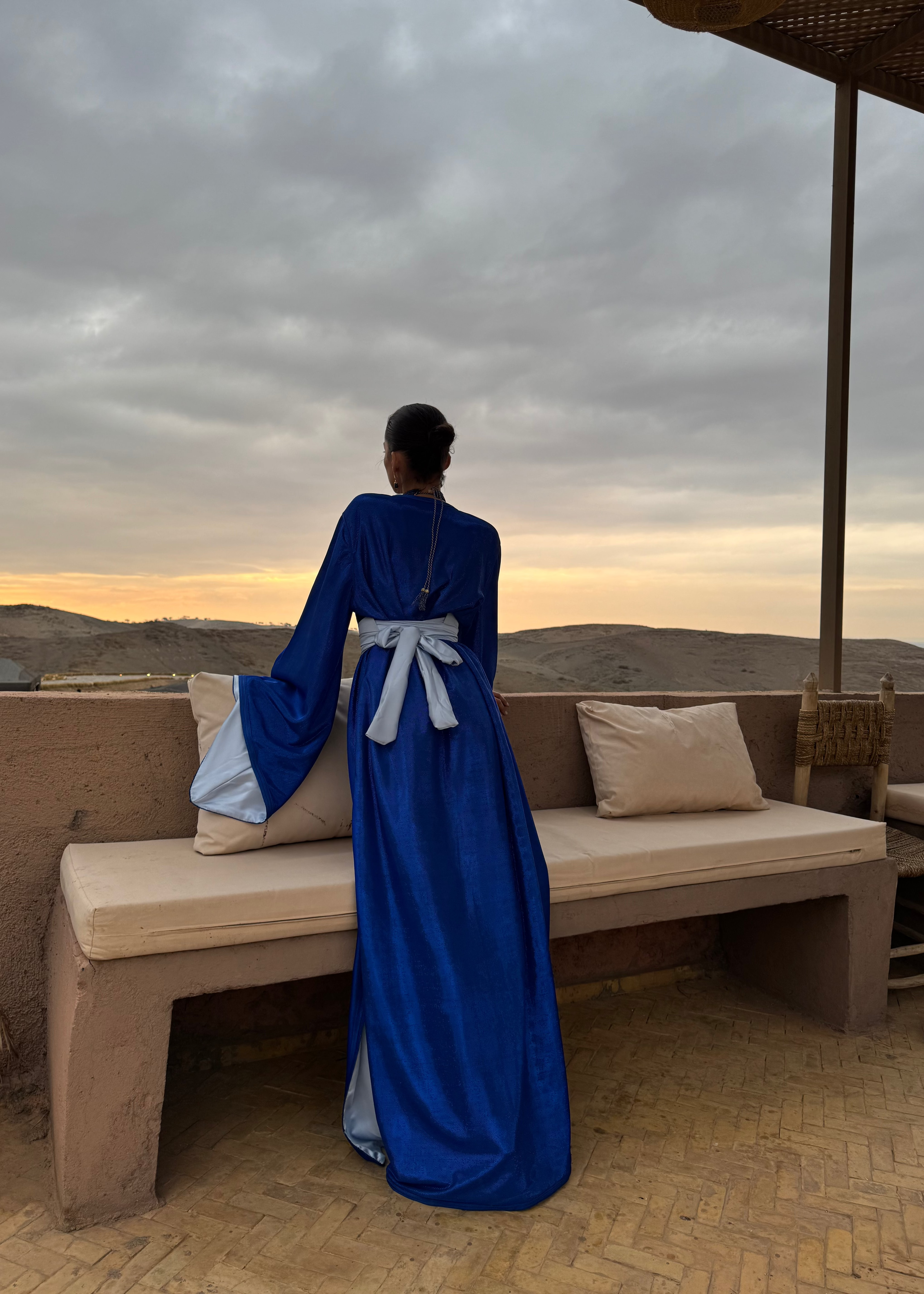 Caftan en lamé de soie bleu pailleté vu de dos, révélant la fluidité du tissu et l’éclat des paillettes au mouvement.