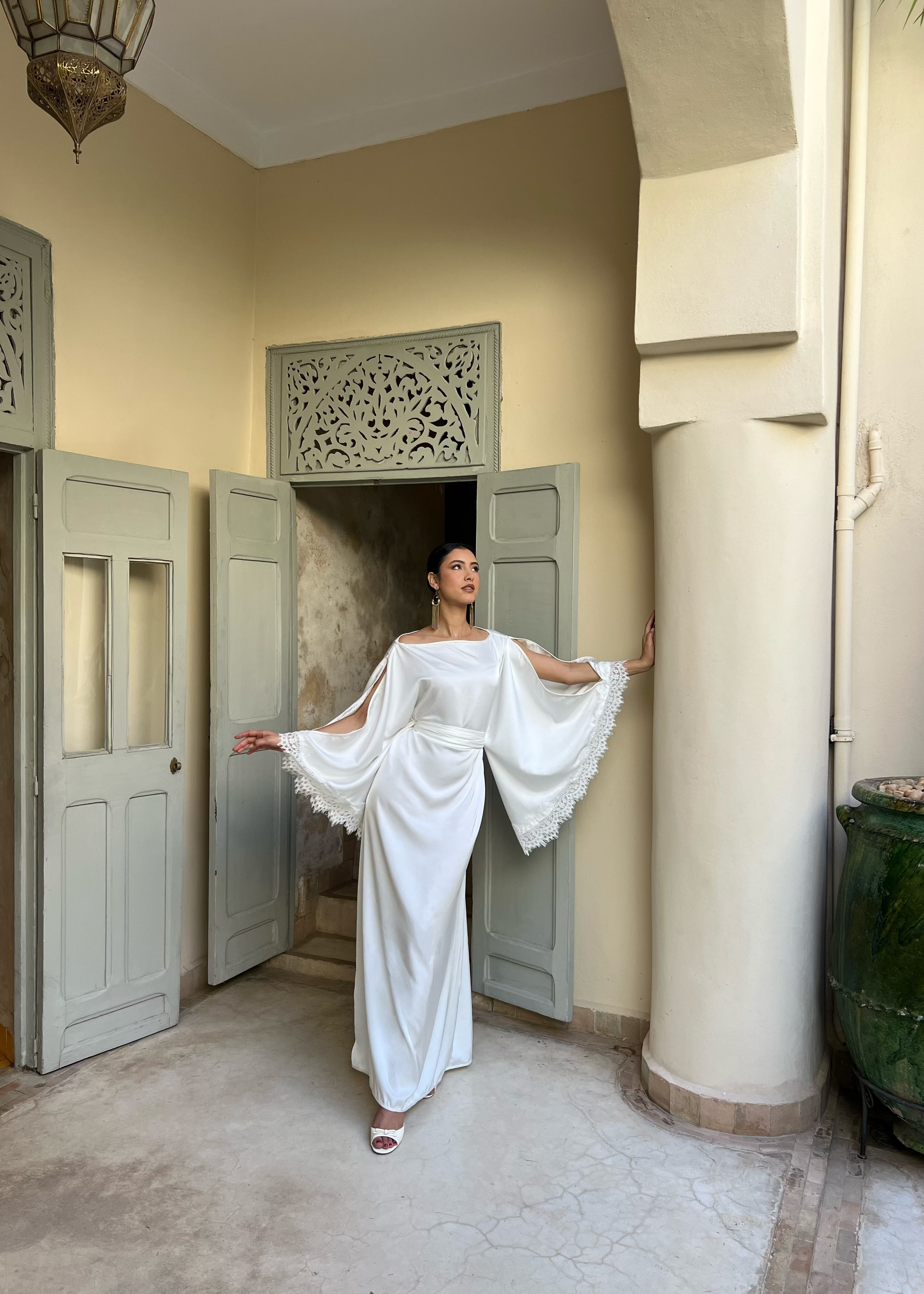 Caftan de mariée en drap de soie blanc, manches ange et bordure en dentelle, vue de face sur mannequin