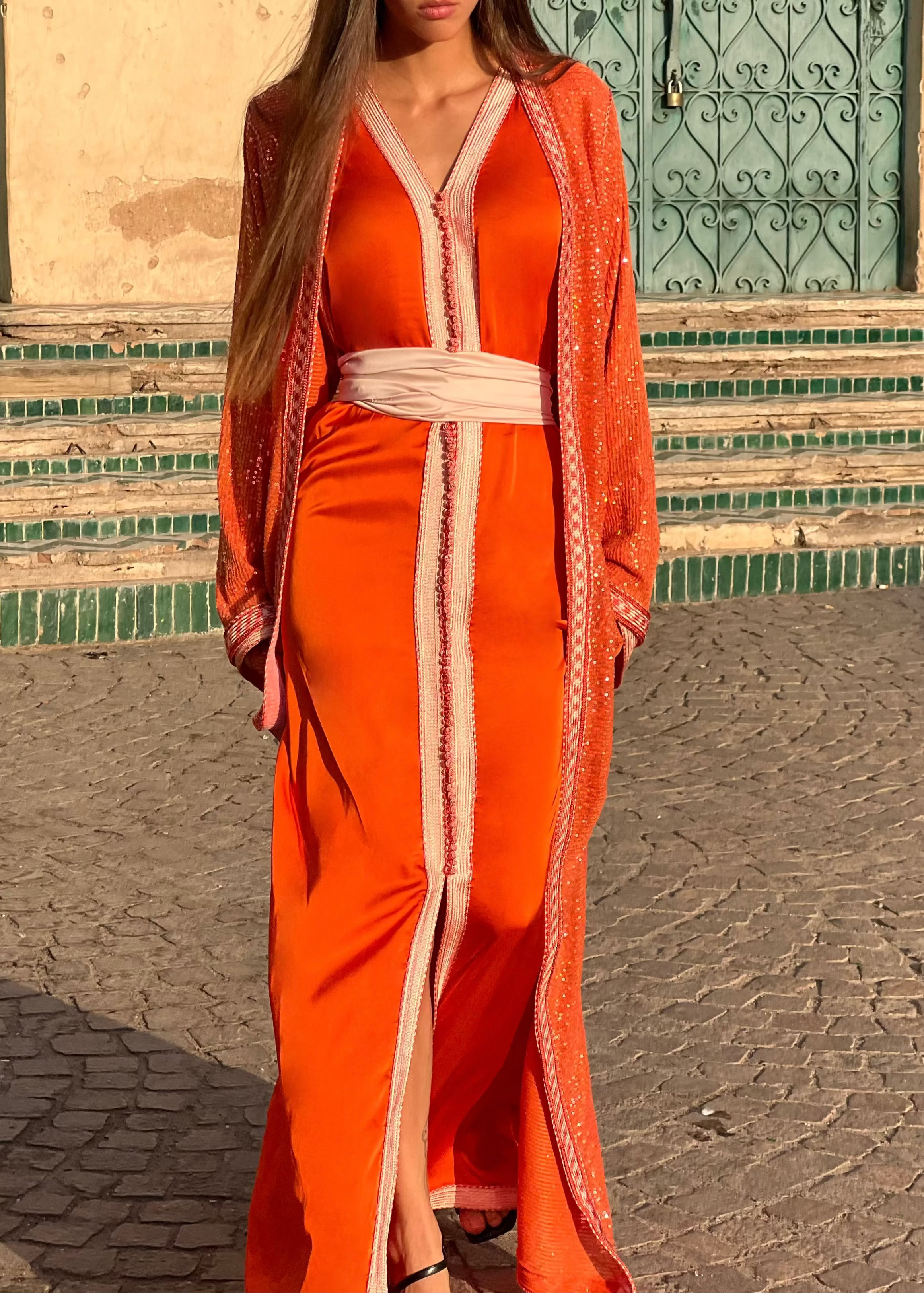 Caftan orange en tulle perlé en mouvement, tissu léger et perles scintillantes sous la lumière