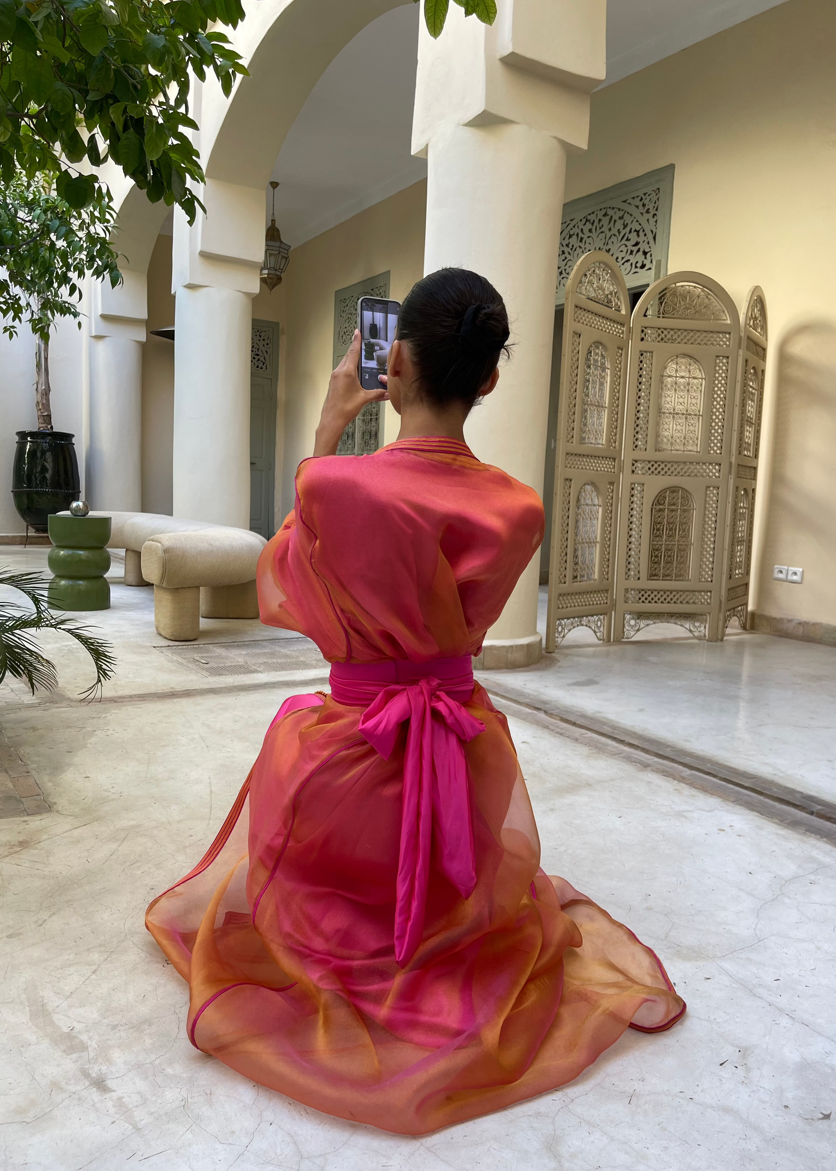Caftan en organza orange et rose vu de dos, révélant la fluidité du tissu et l’harmonie vibrante des deux teintes.