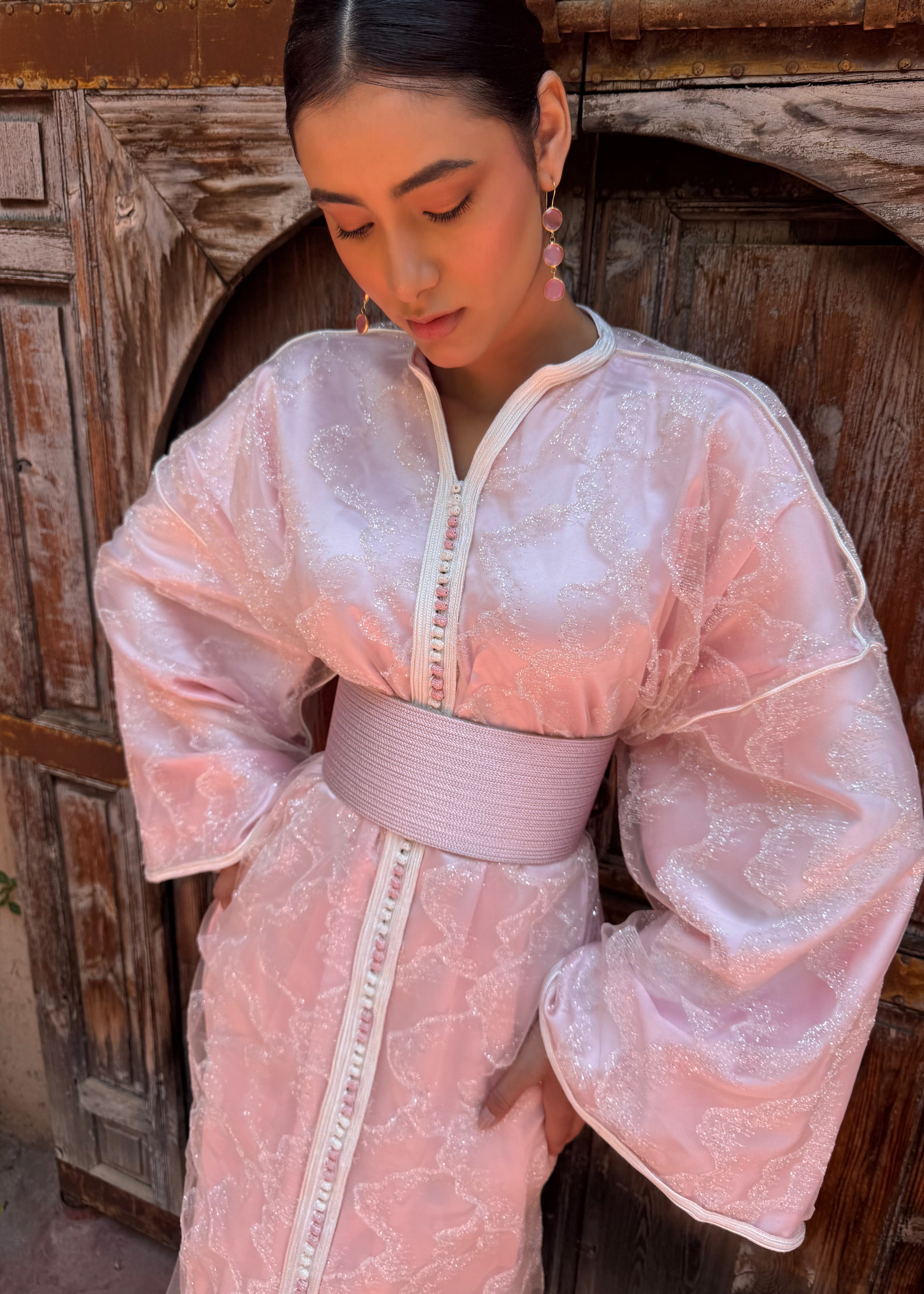 Zoom sur le tissu en tulle pailleté du caftan rose, détail des paillettes et de la matière