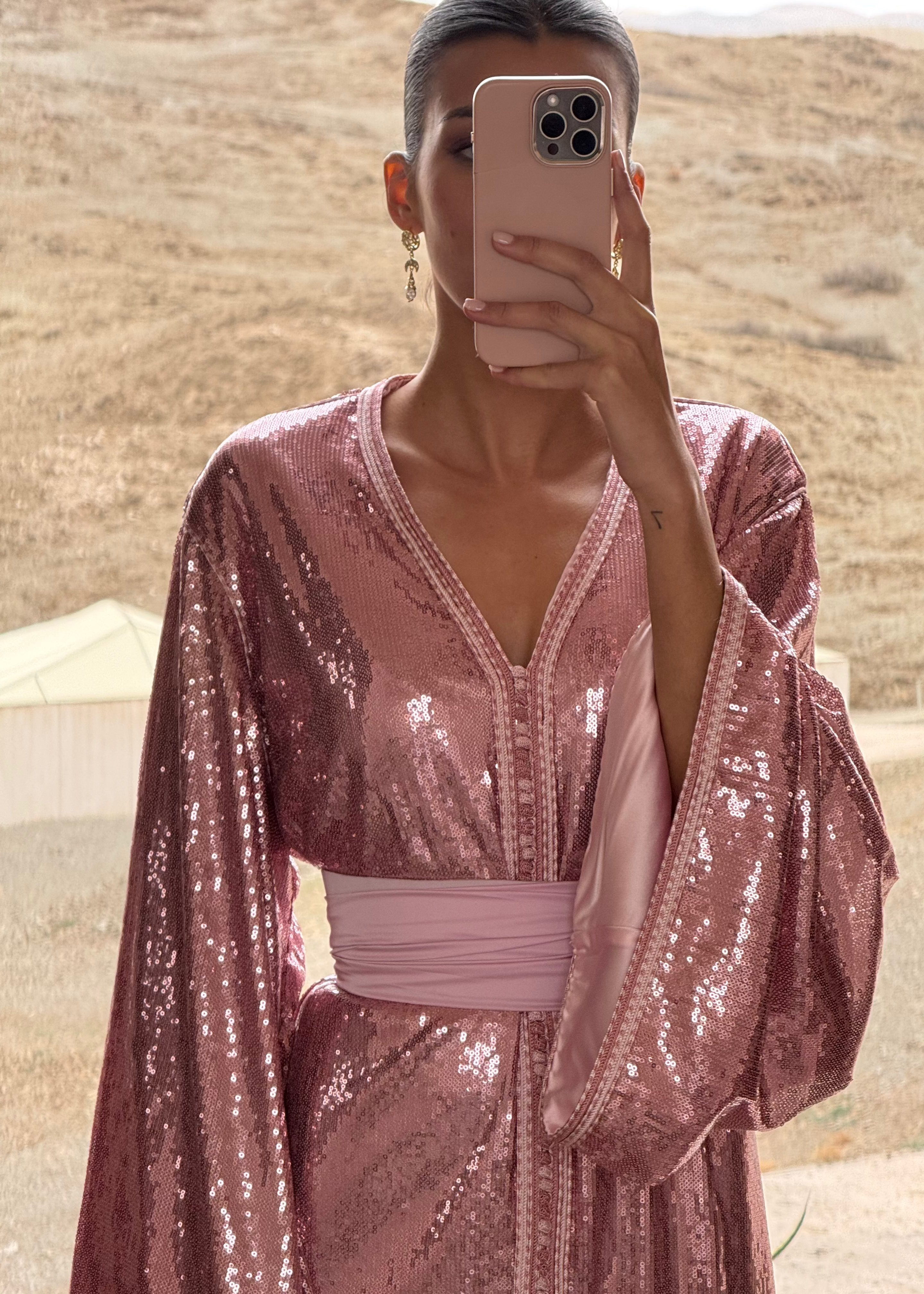 Caftan en sequins rose vu de profil, soulignant la luminosité des sequins et l’élégance de la silhouette.