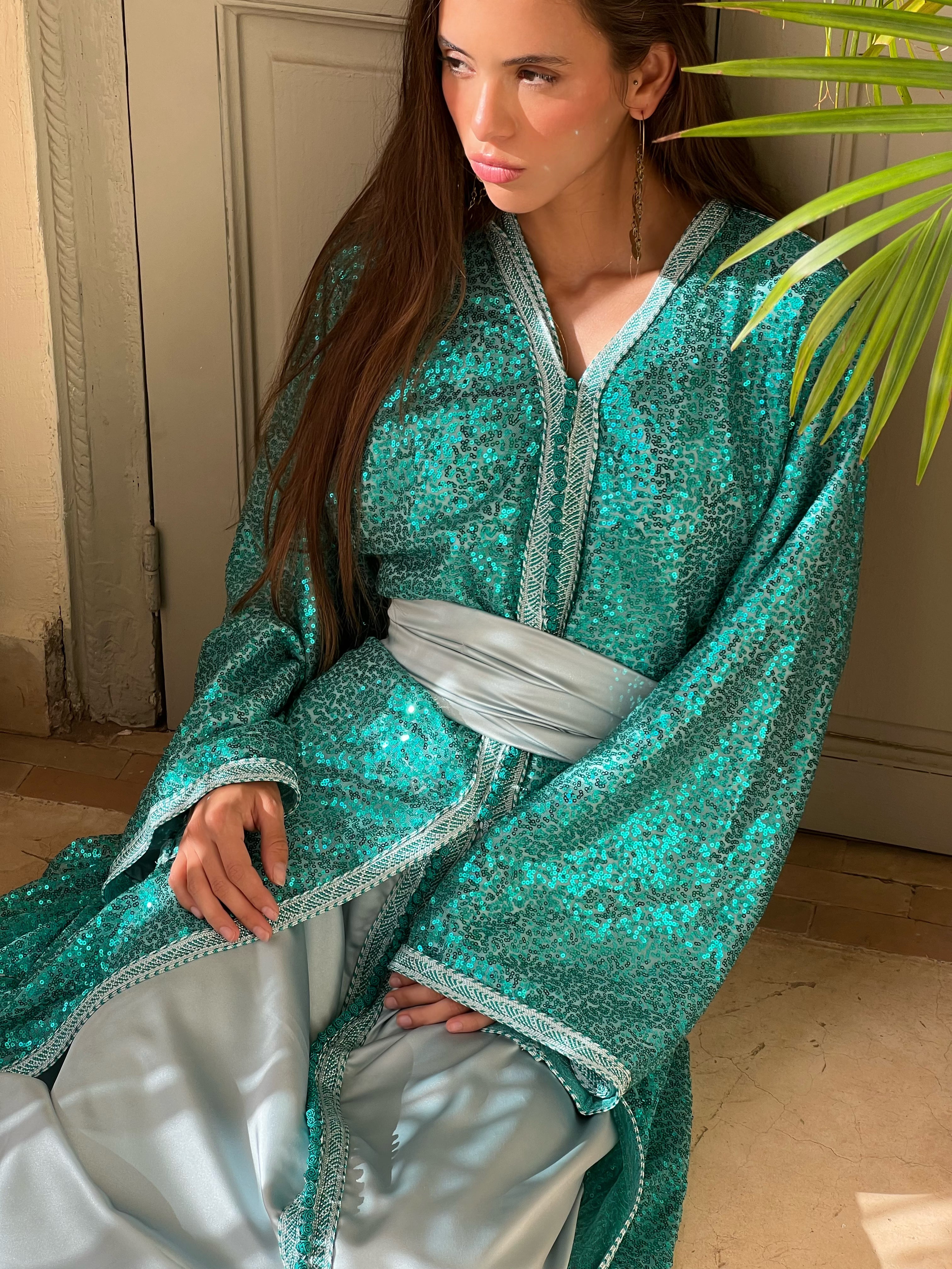 Caftan turquoise en tulle pailleté avec doublure en soie, vue assise élégante mettant en valeur la fluidité du drapé