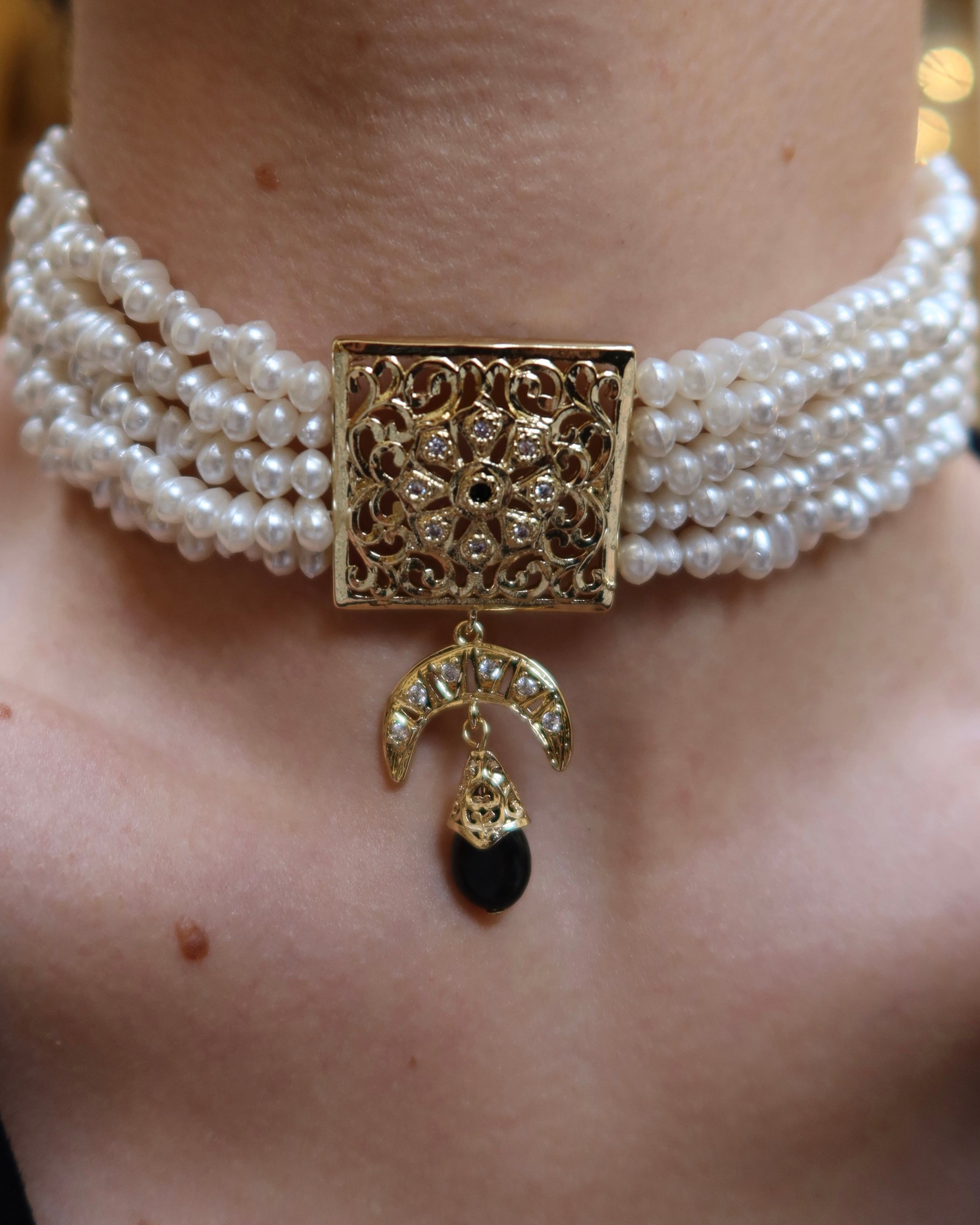 Close-up of the medallion and beads on the gold and black necklace