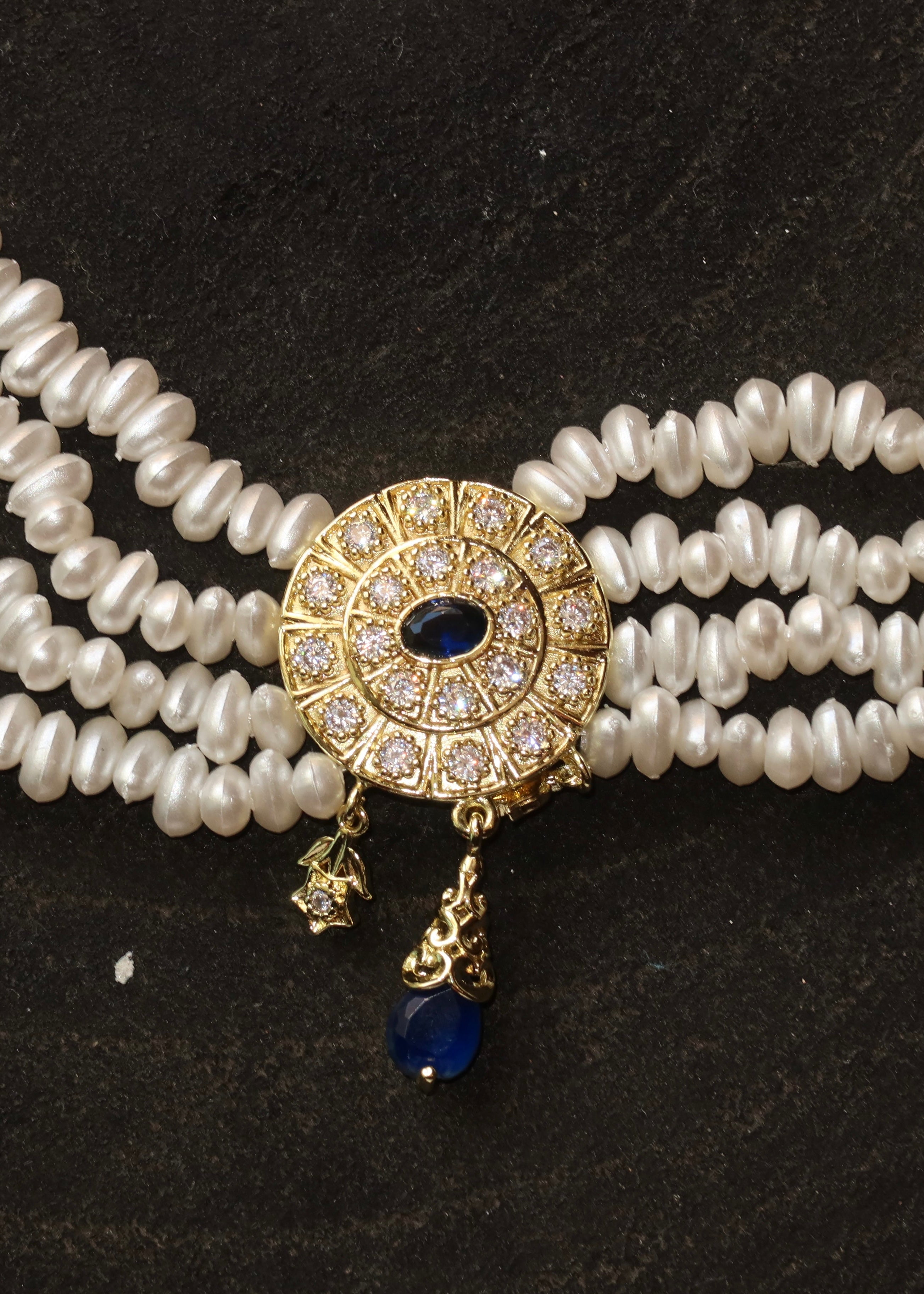 A blue medallion choker necklace worn close to the neck