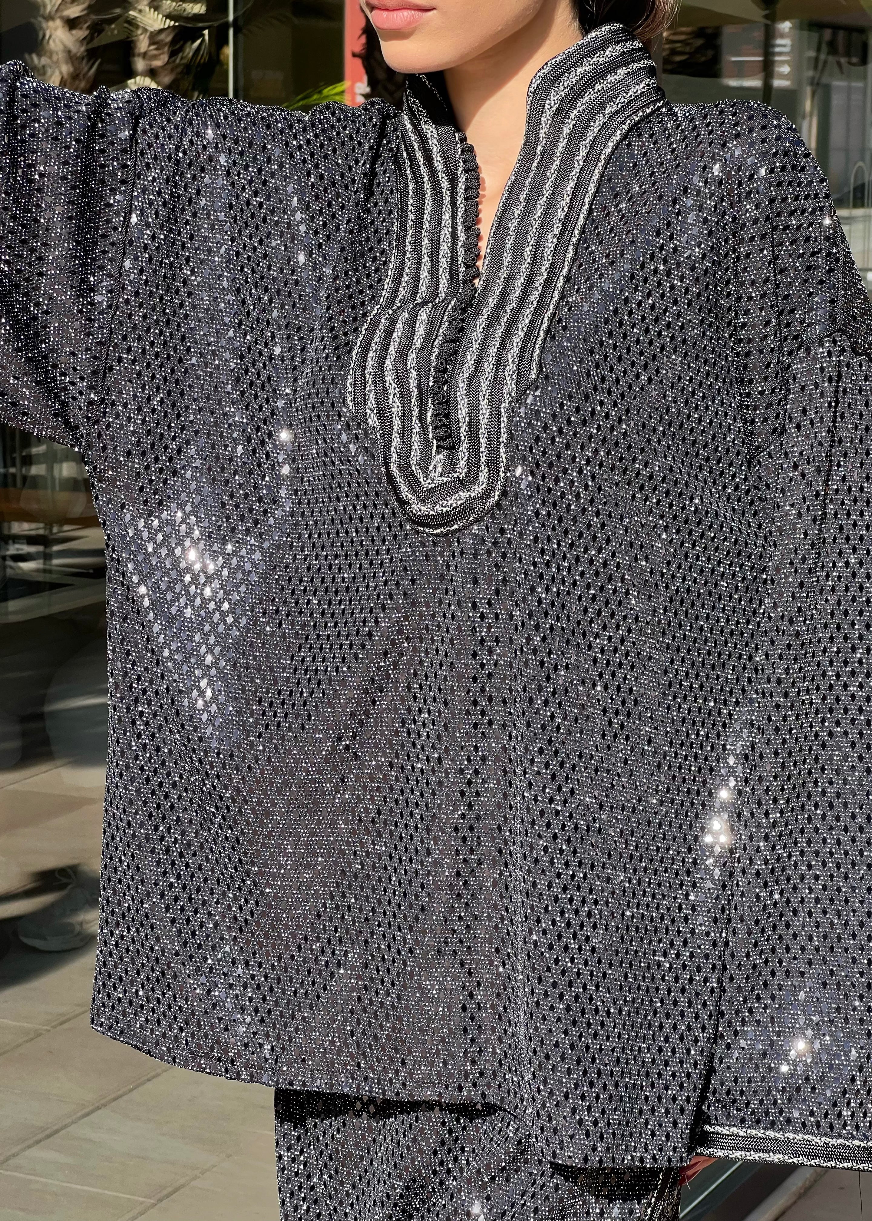 Détail du jacquard noir scintillant et de la sfifa sur l’ensemble chemise et pantalon, couture artisanale et texture luxueuse