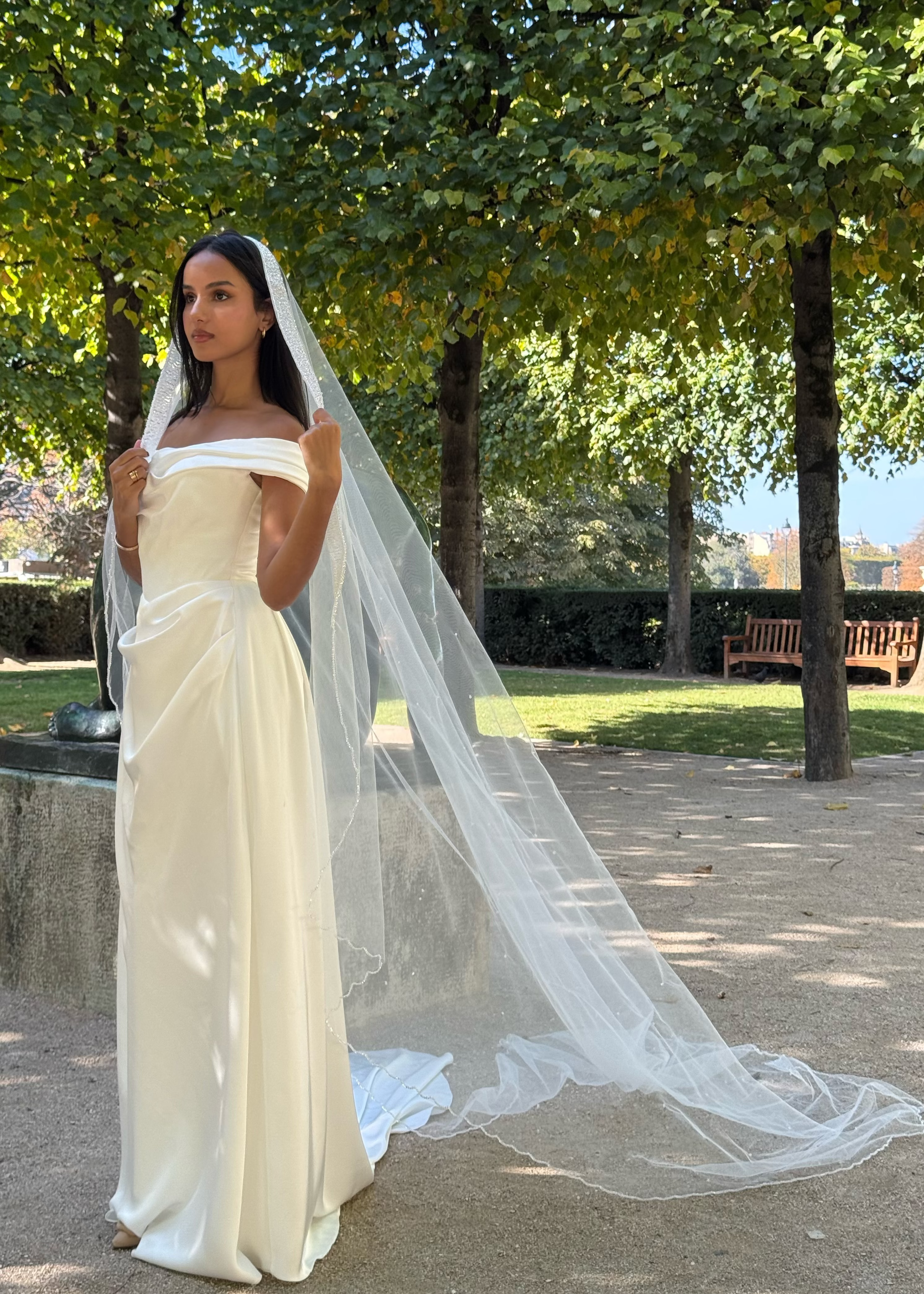 Mariée de dos avec un voile long orné de perles et d’une bordure lumineuse scintillante.