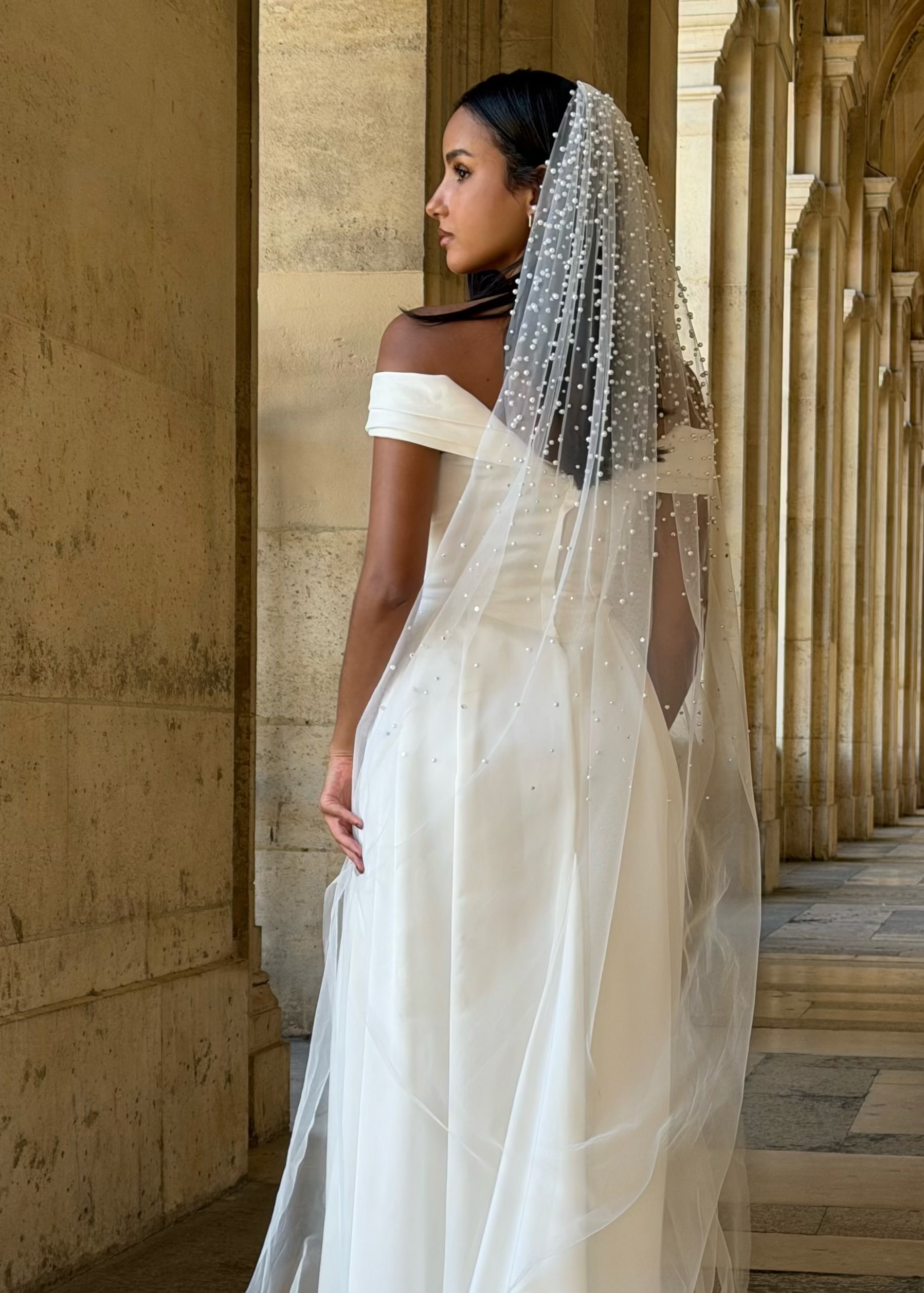 Vue de dos d’un voile de mariée long en tulle transparent avec perles brodées sur toute la longueur.