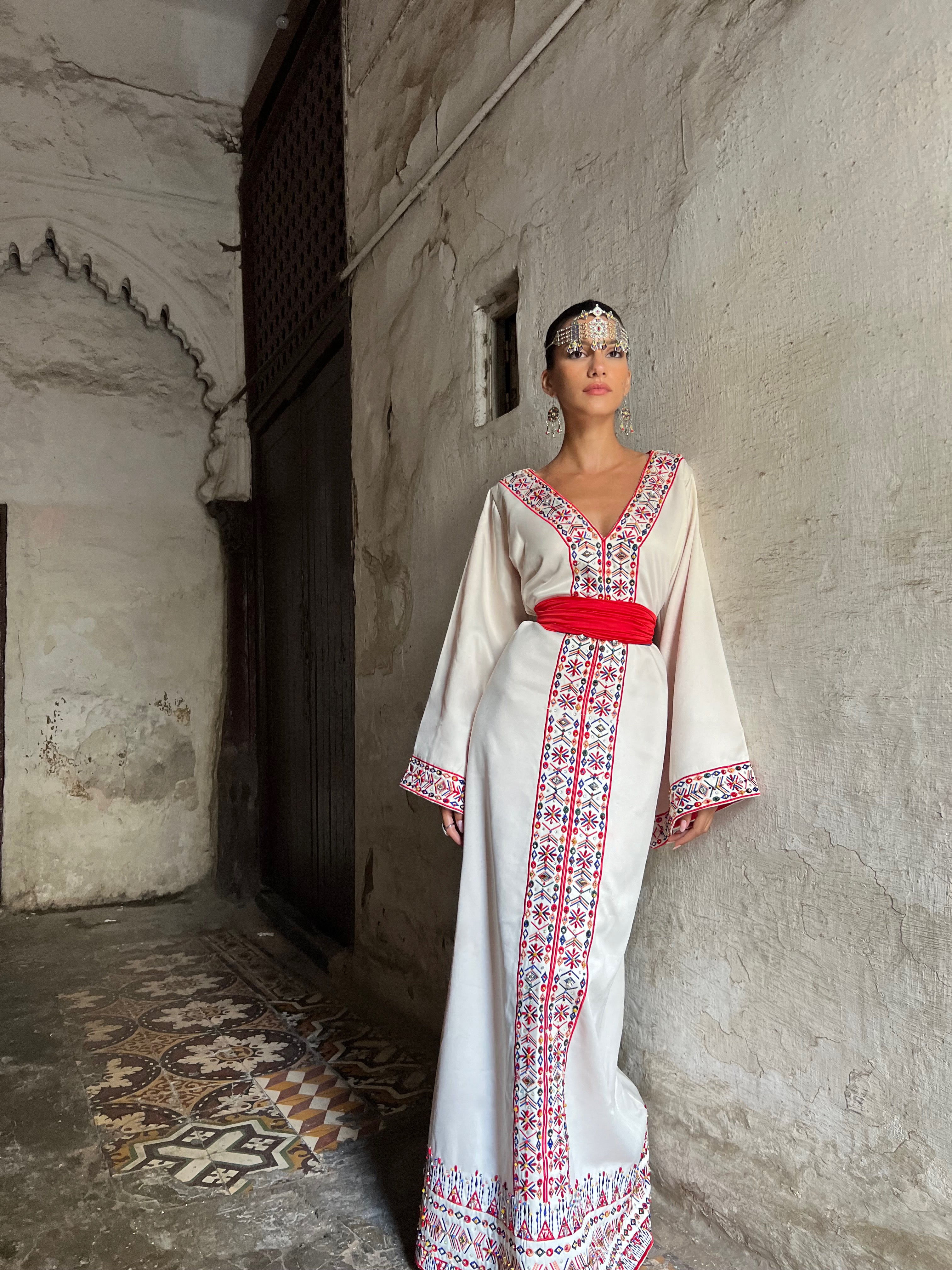 Embroidered Kabyle Kaftan captured in motion, highlighting the fluidity of the fabric and the reflections of the colorful embroidery threads.