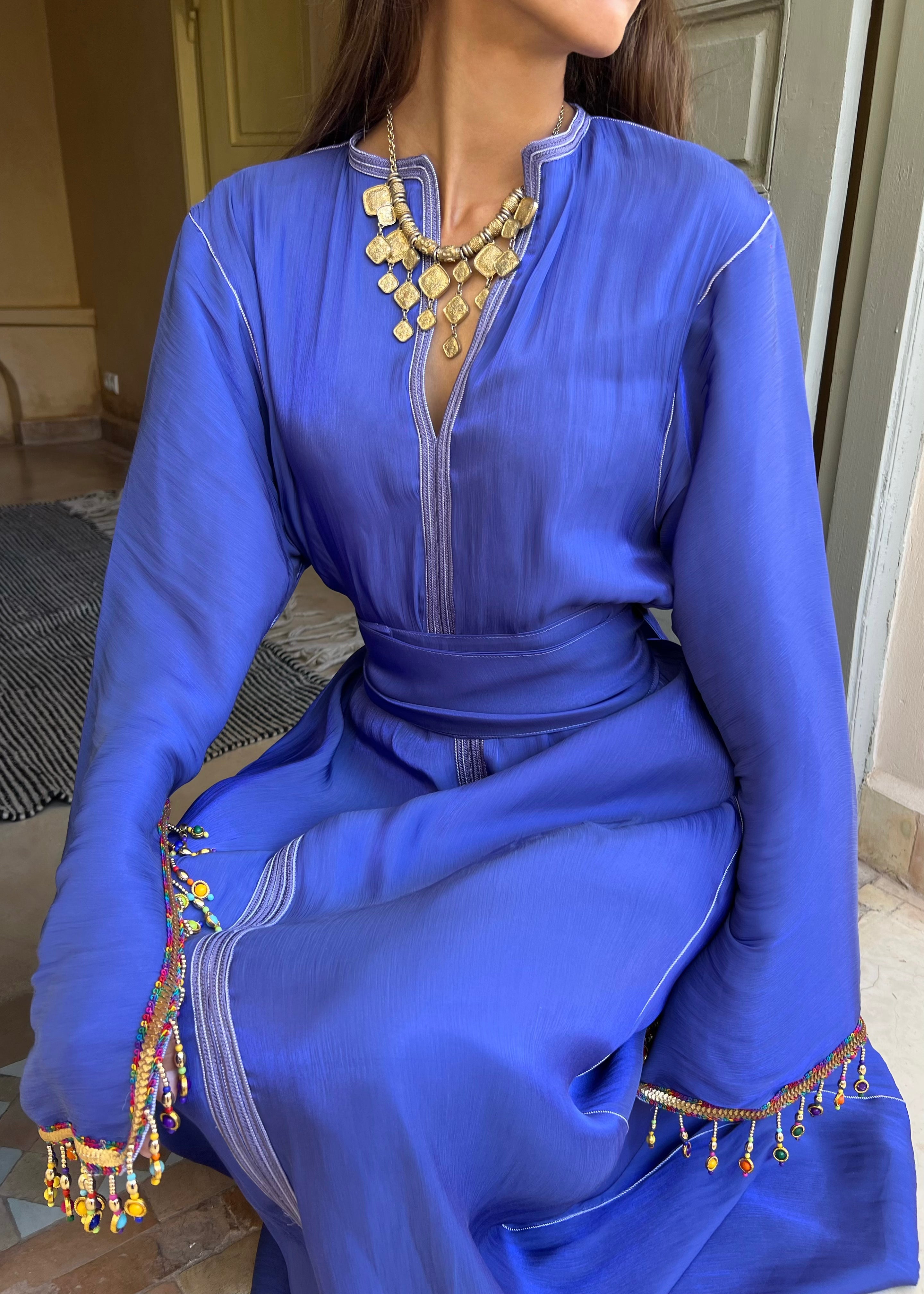 Kaftan in blue silk fabric with embroidery, seated view highlighting the fluidity of the fabric and the richness of the craftsmanship