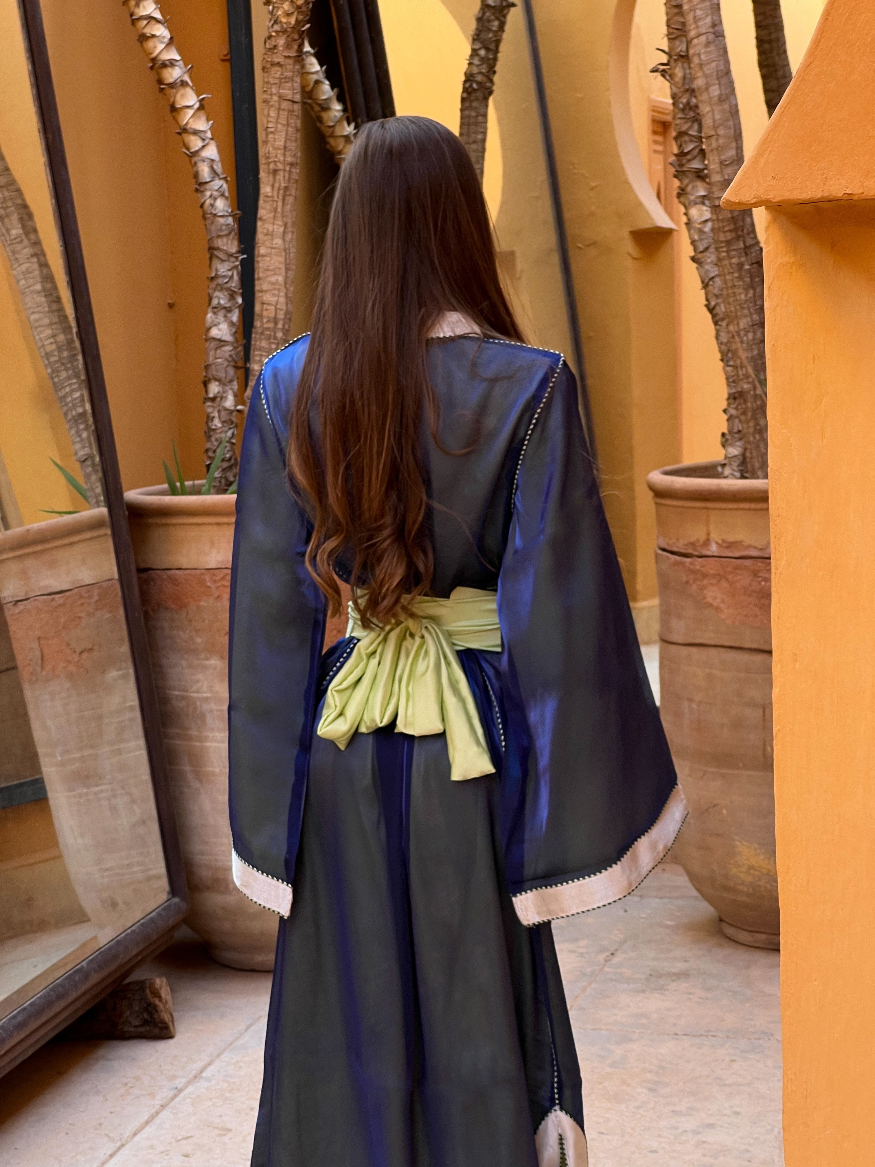 Kaftan in blue organza seen from the back, revealing the delicate transparency of the fabric and the fluidity of the fall.