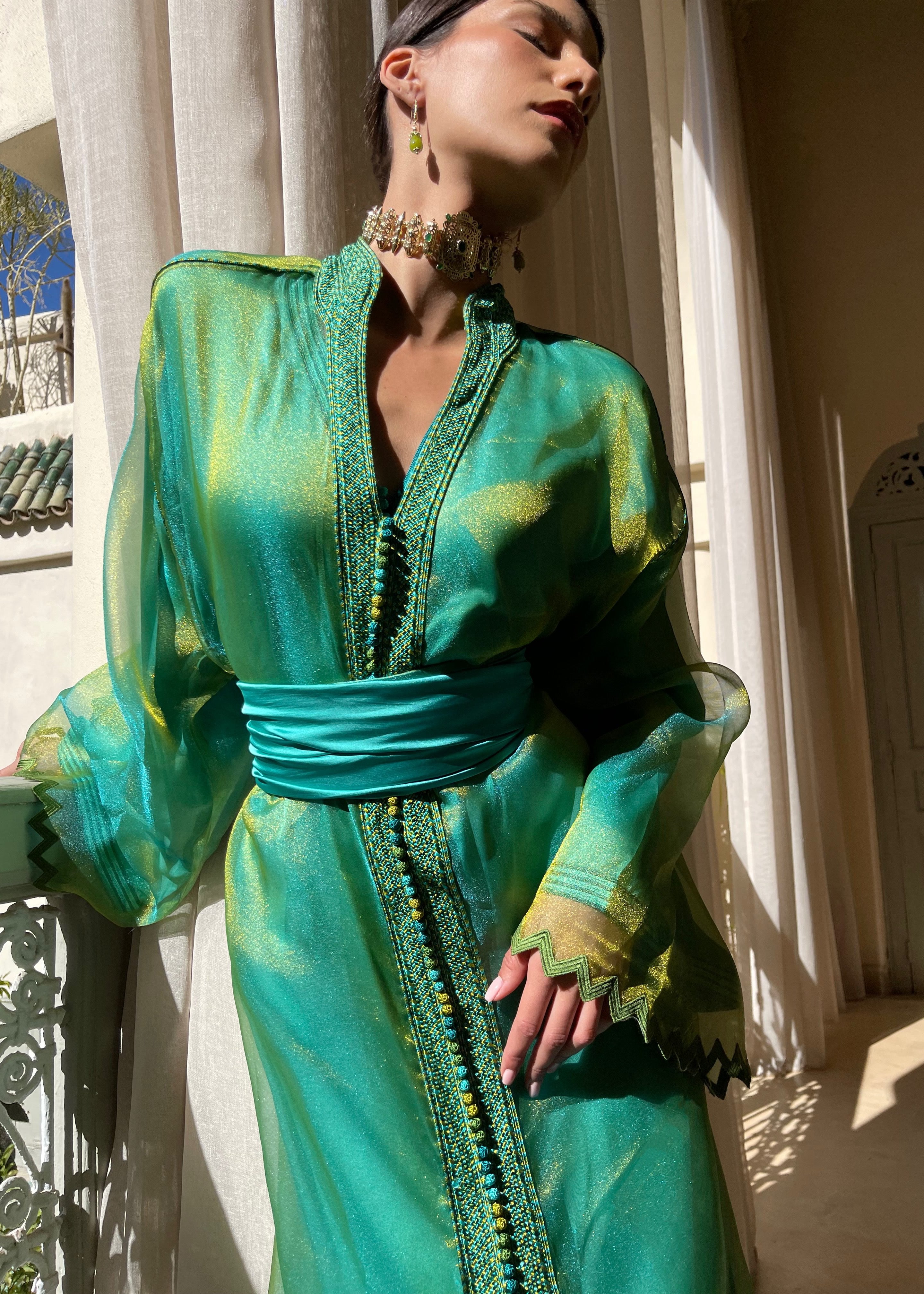 Kaftan in green and blue organza captured in motion, highlighting the fluidity of the fabric and the play of light between the hues.