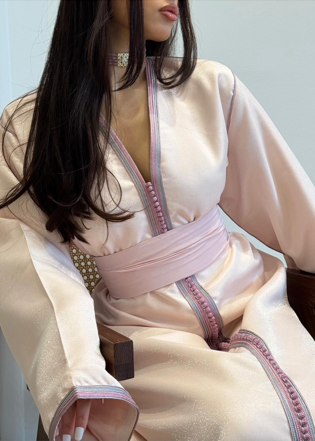 Pink satin Kaftan seen from the back, revealing the fluidity of the fabric and the finesse of the finishing touches.