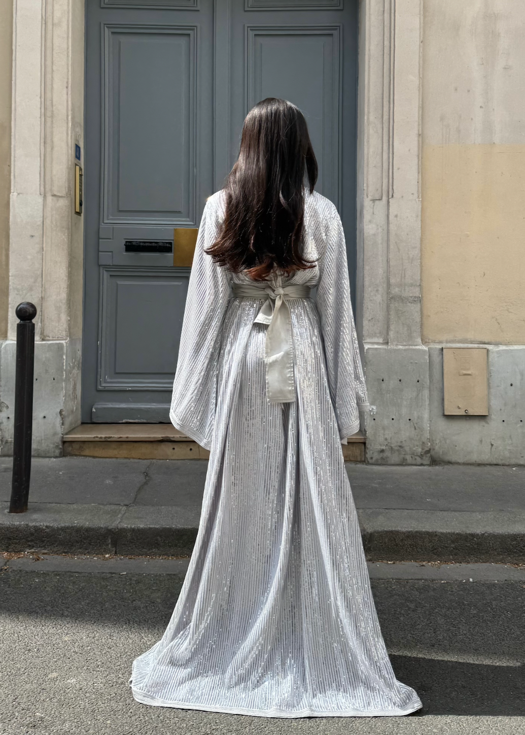 Kaftan in silver-beaded tulle seen from the back, revealing the delicate transparency of the tulle and the finesse of the silver beads.