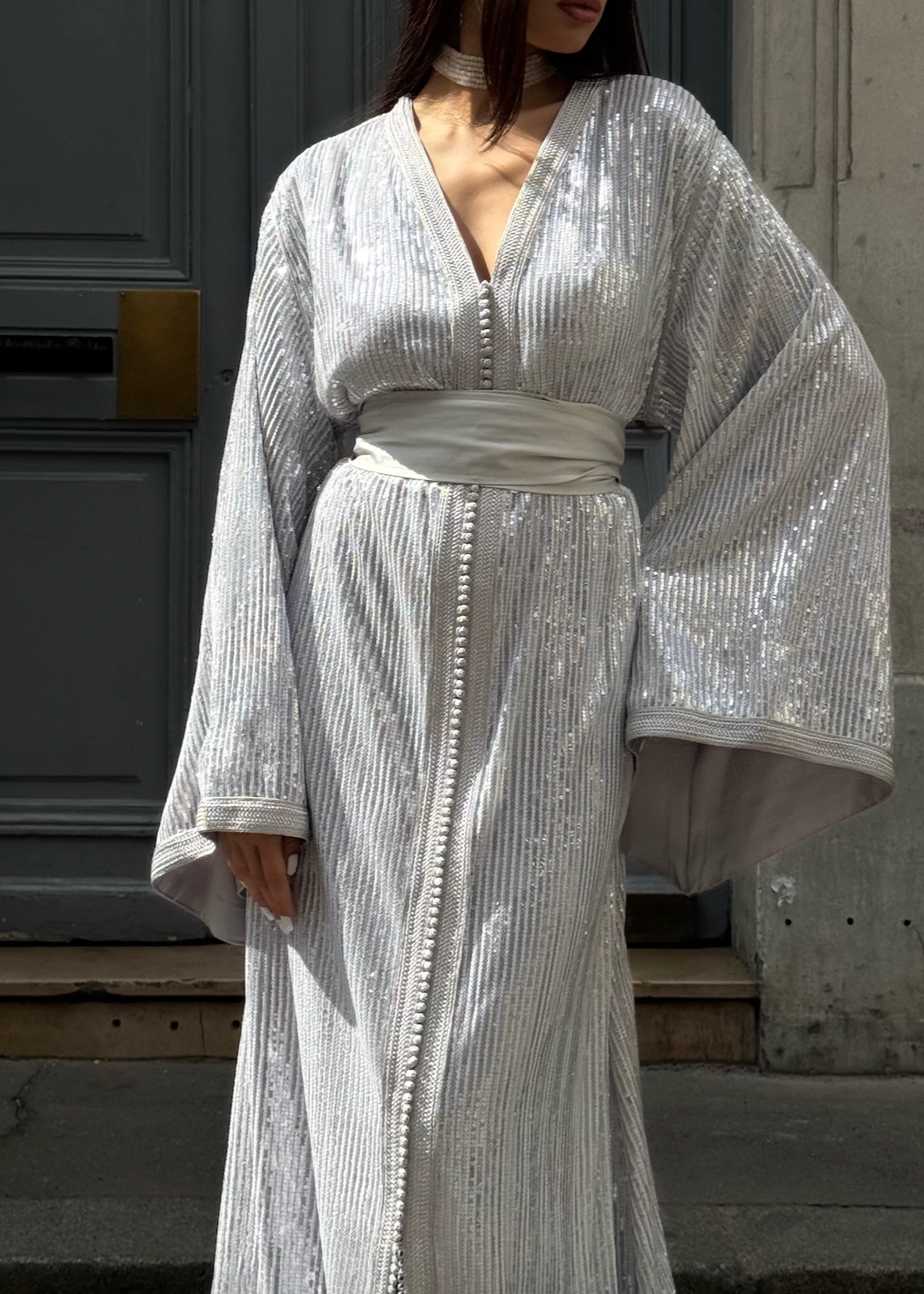 Kaftan in silver-beaded tulle captured in motion, highlighting the lightness of the fabric and the luminous reflections of the pearls.