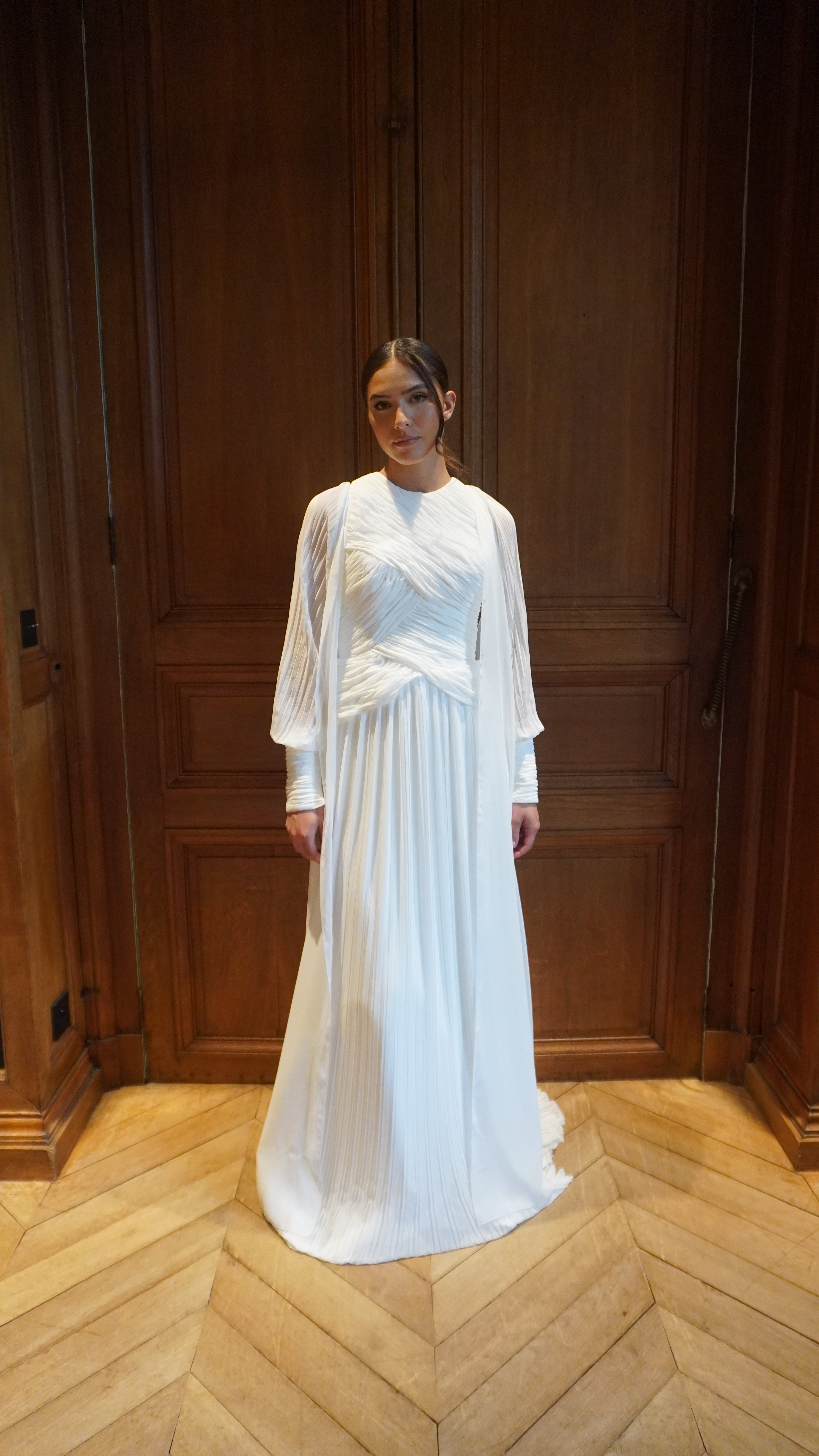 Full-length view of a mannequin wearing a pleated bridal cape in lightweight tulle