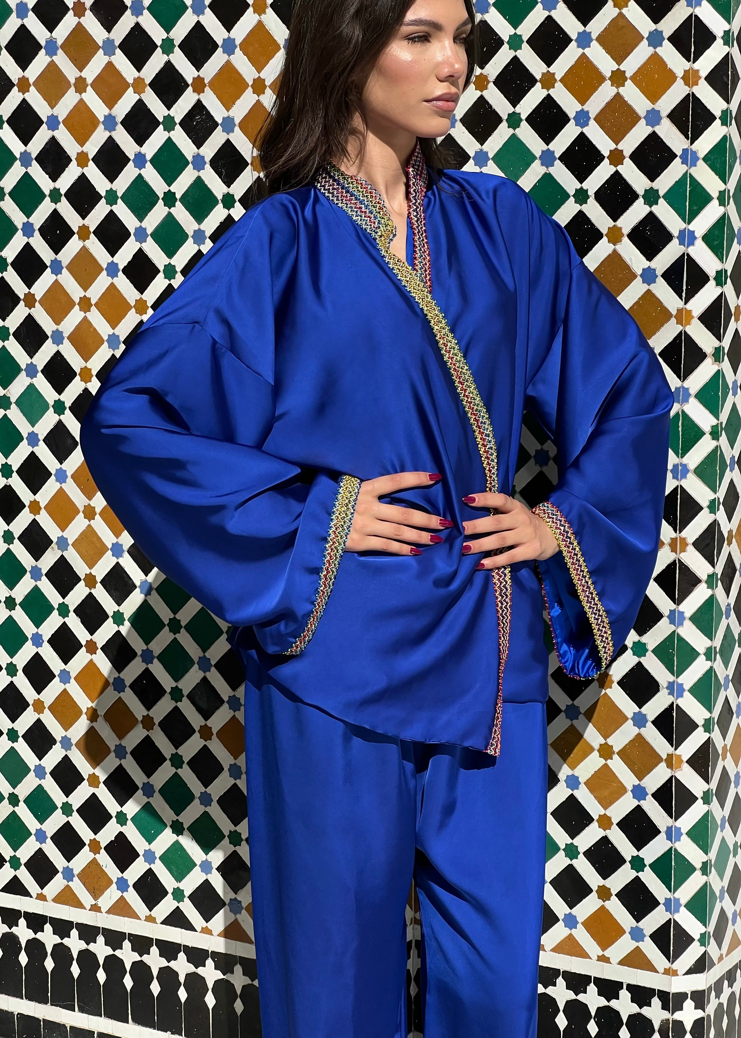 Profile of ensemble in blue silk cloth, shirt with Kabyle embroidery on collar and elegant flowing pants.