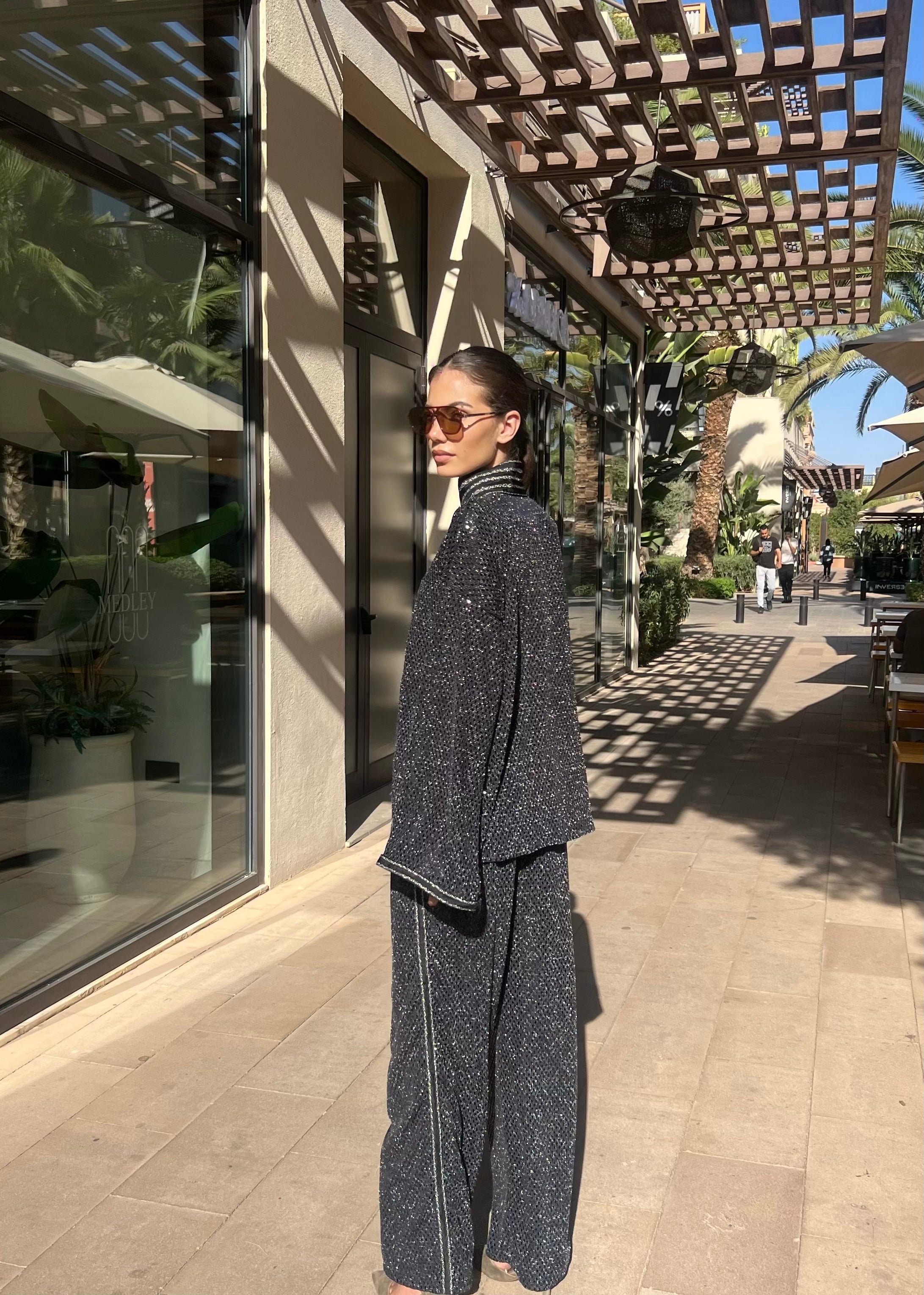 Back of ensemble in shimmering black jacquard adorned with sfifa, hand-crafted finishes and fluid fall of shiny fabric