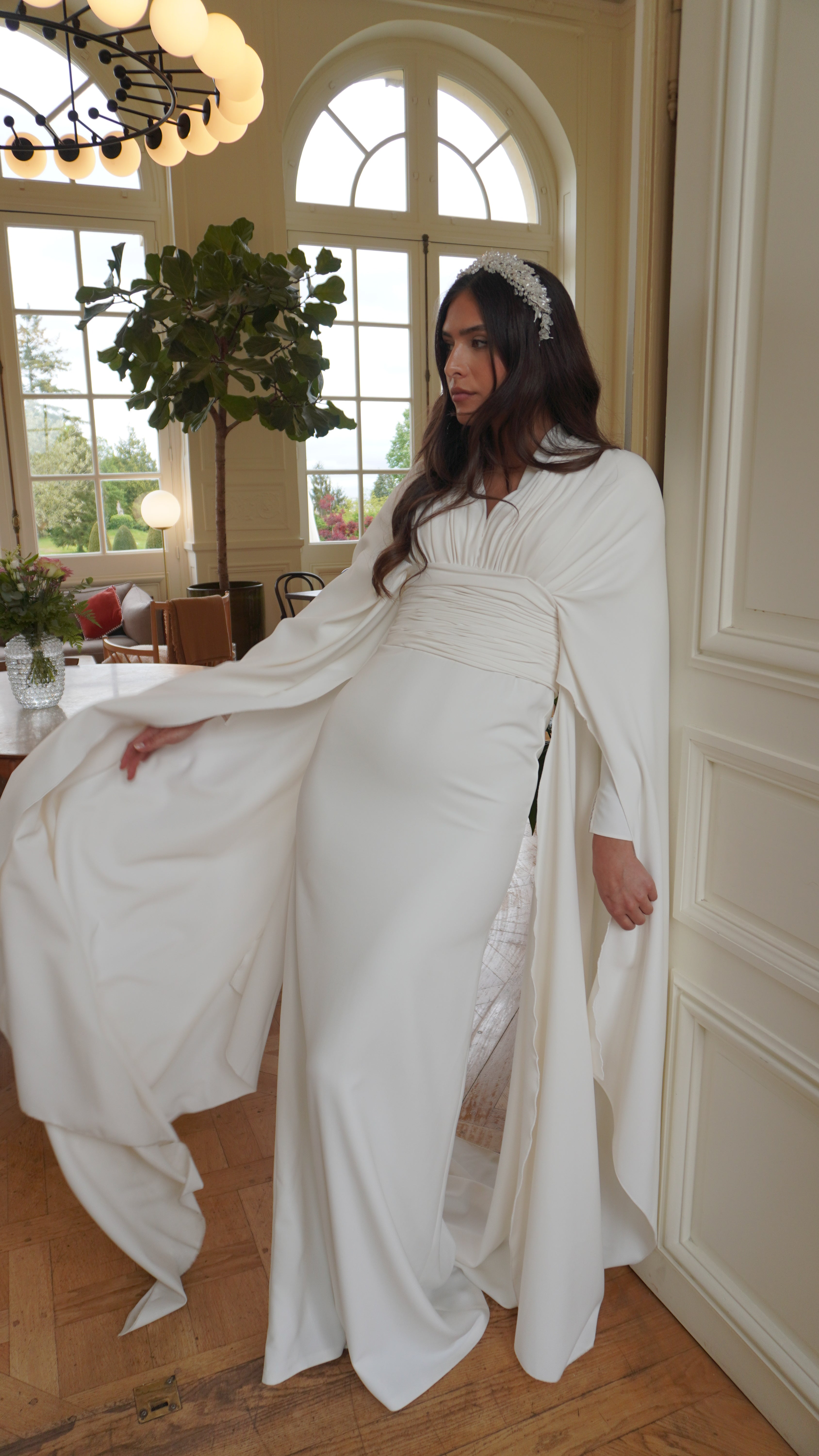 Bohemian-chic wedding dress with cape sleeves captured in motion, highlighting the lightness of the fabric and the fluidity of the cape.