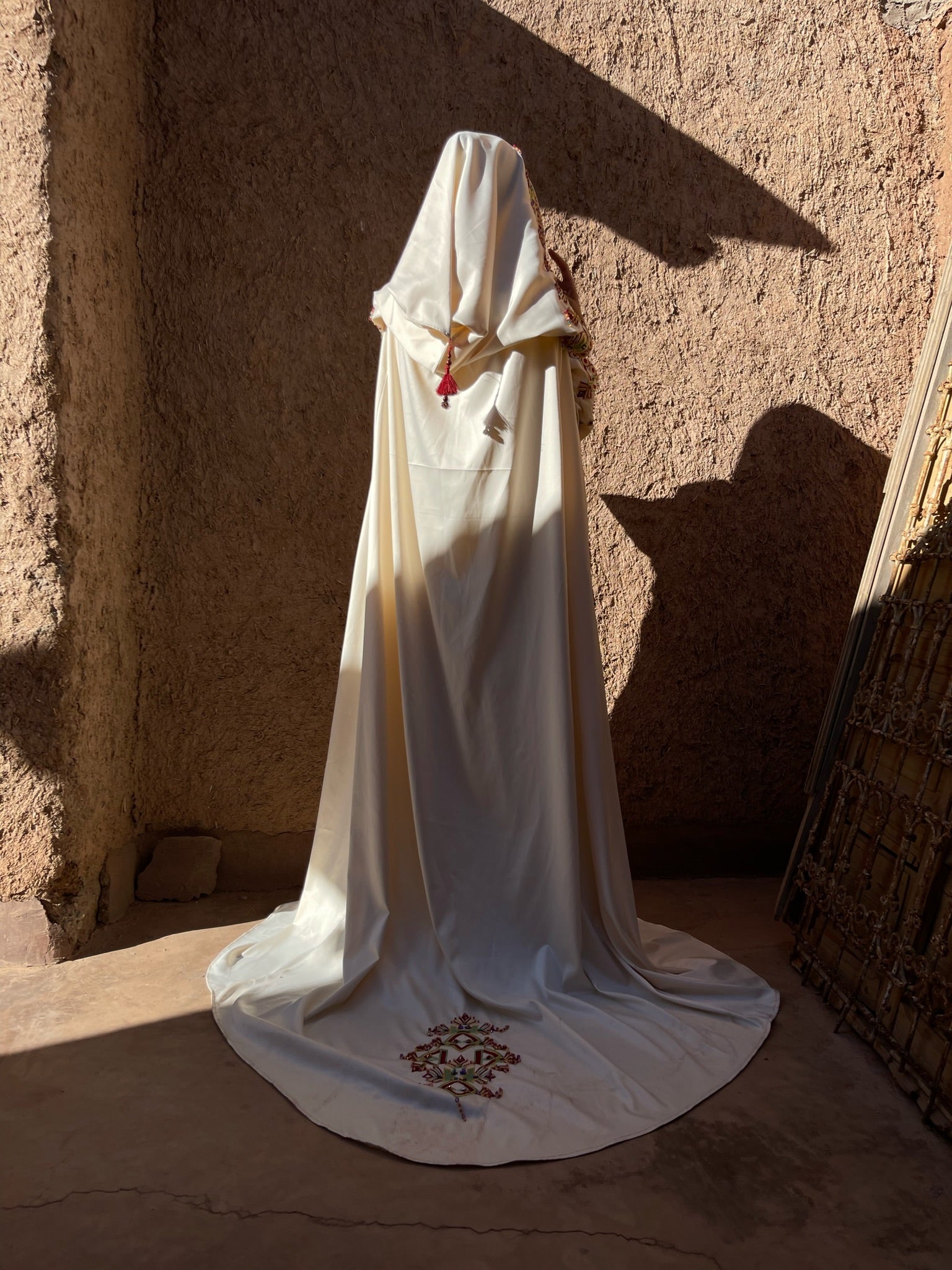 Kabyle wedding dress with bournous seen from the back, revealing the elegant drape of the bournous and the handcrafted finishing of the costume.