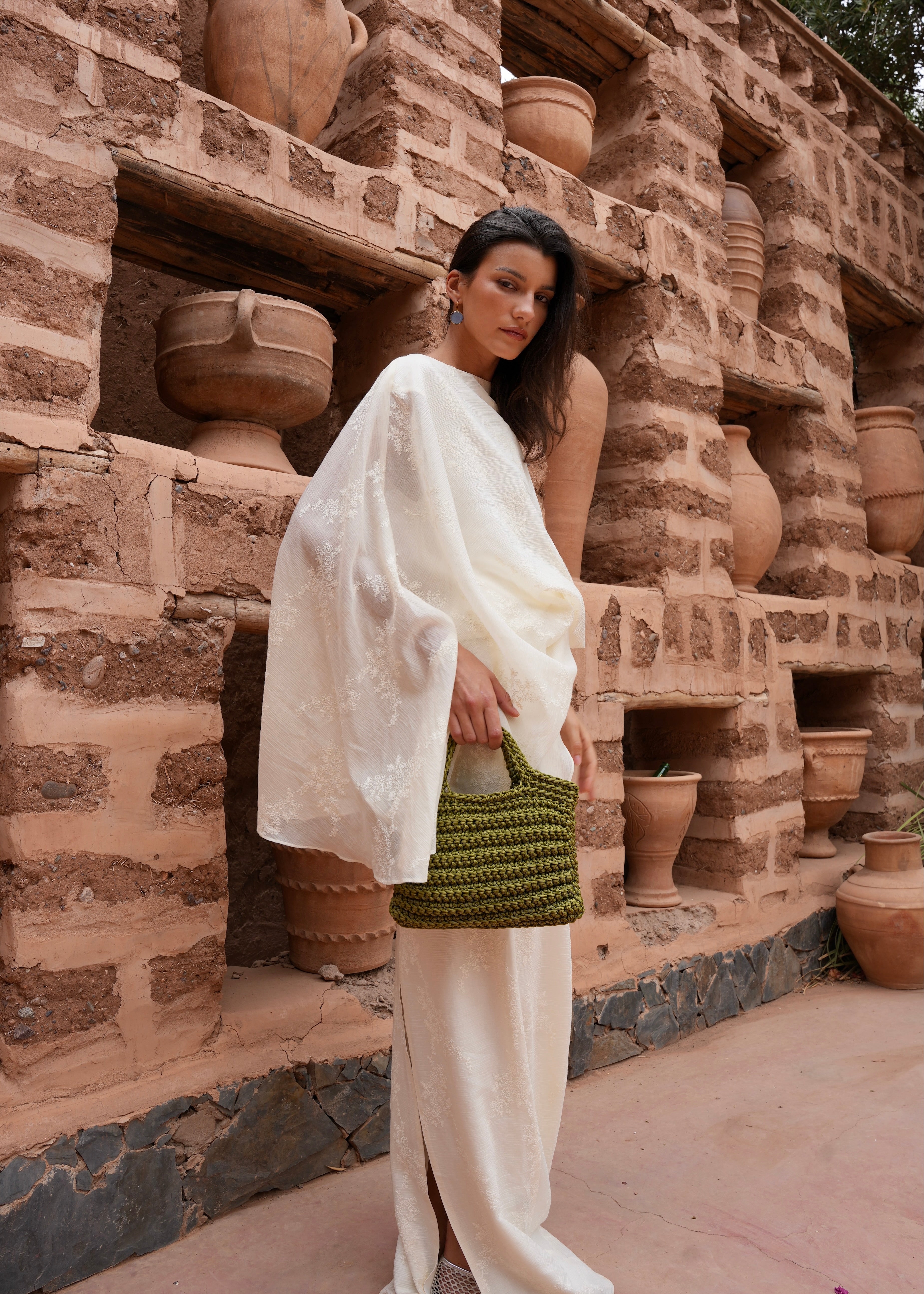 Full-length view of a model wearing the khaki green crochet square bag, natural style