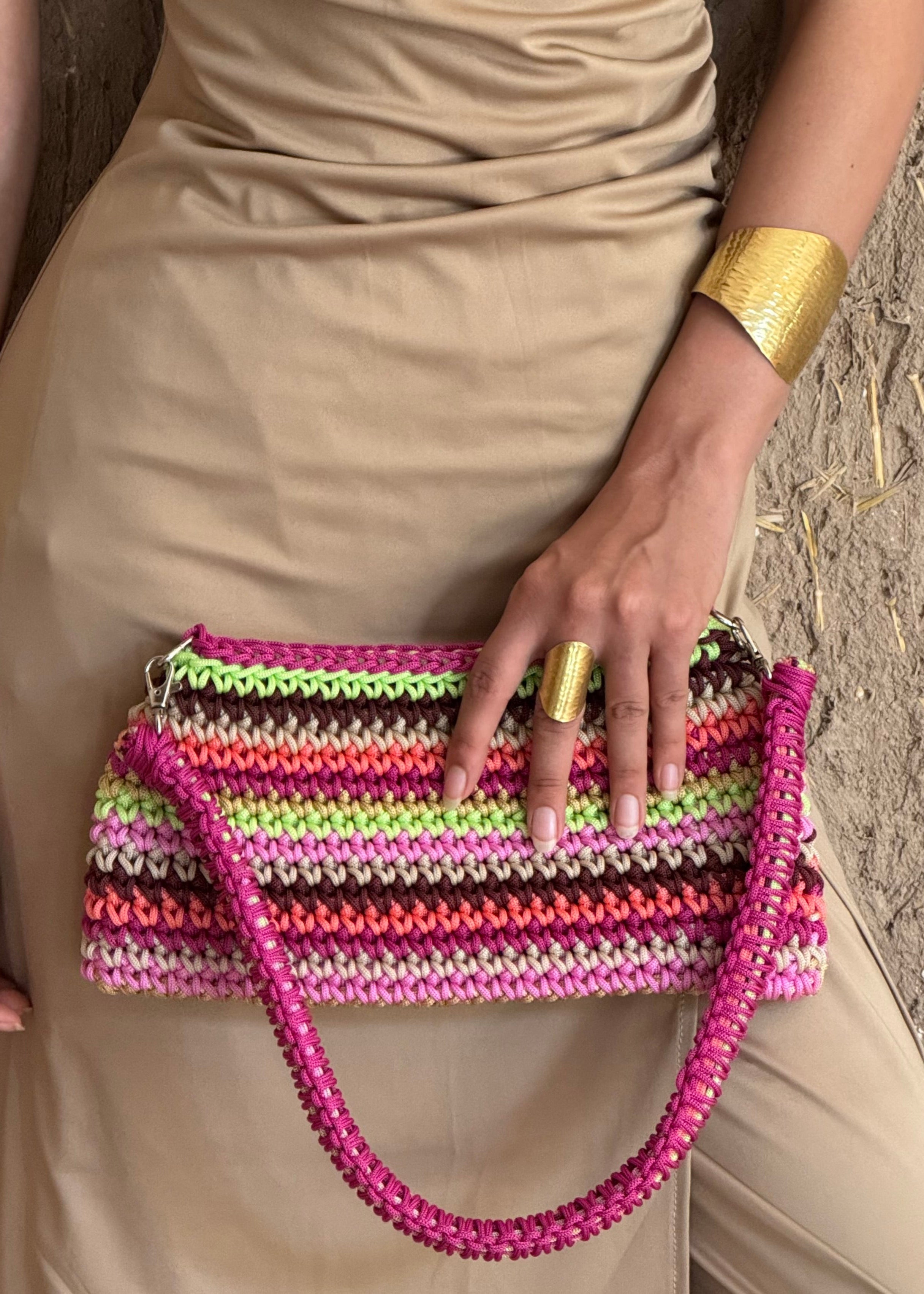 Zoom on the multicolored pink crochet trapeze bag carried by hand, visible details