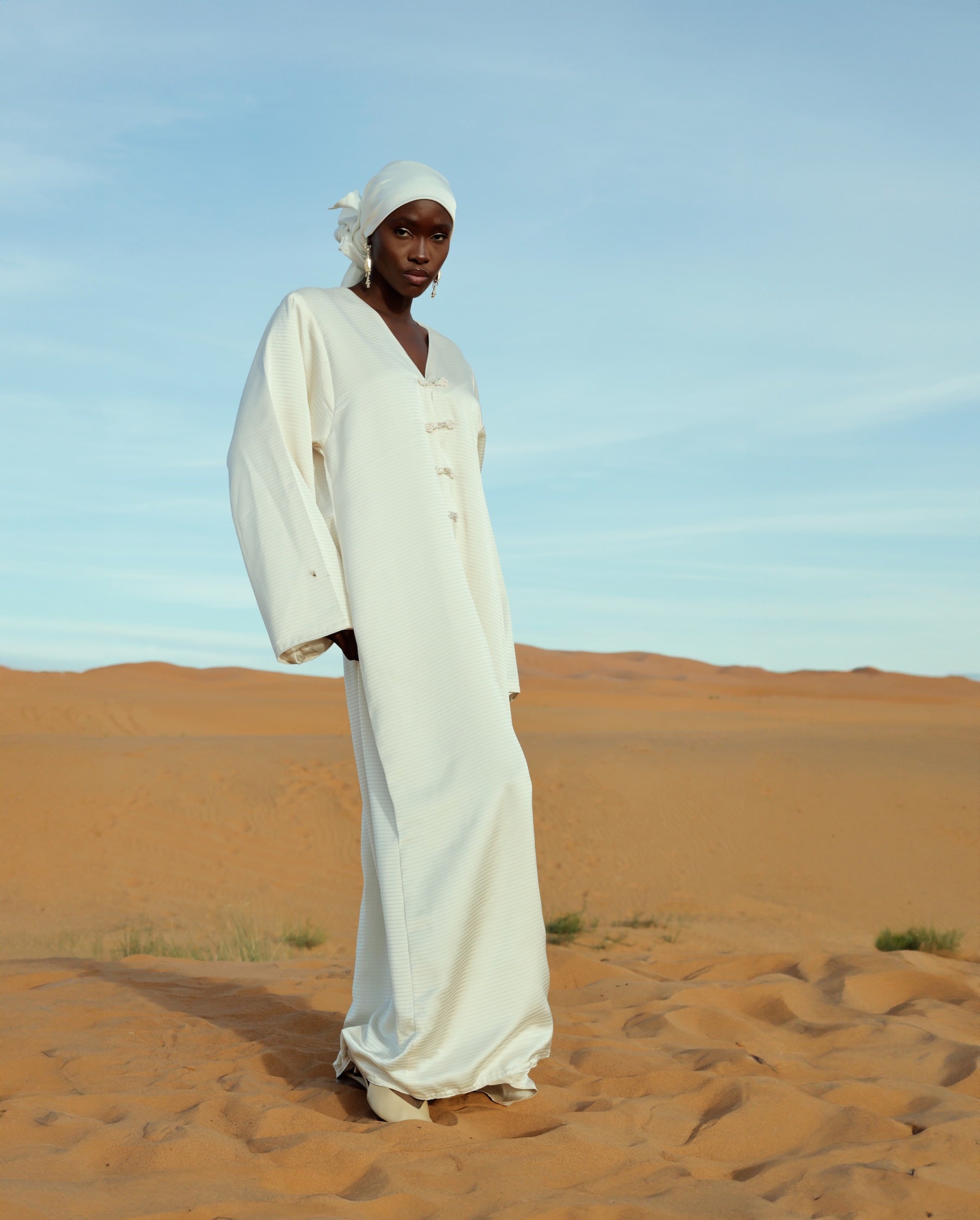 فستان أبيض من الساتان المطوي يرتدى أثناء الحركة، قماش انسيابي وأنيق.