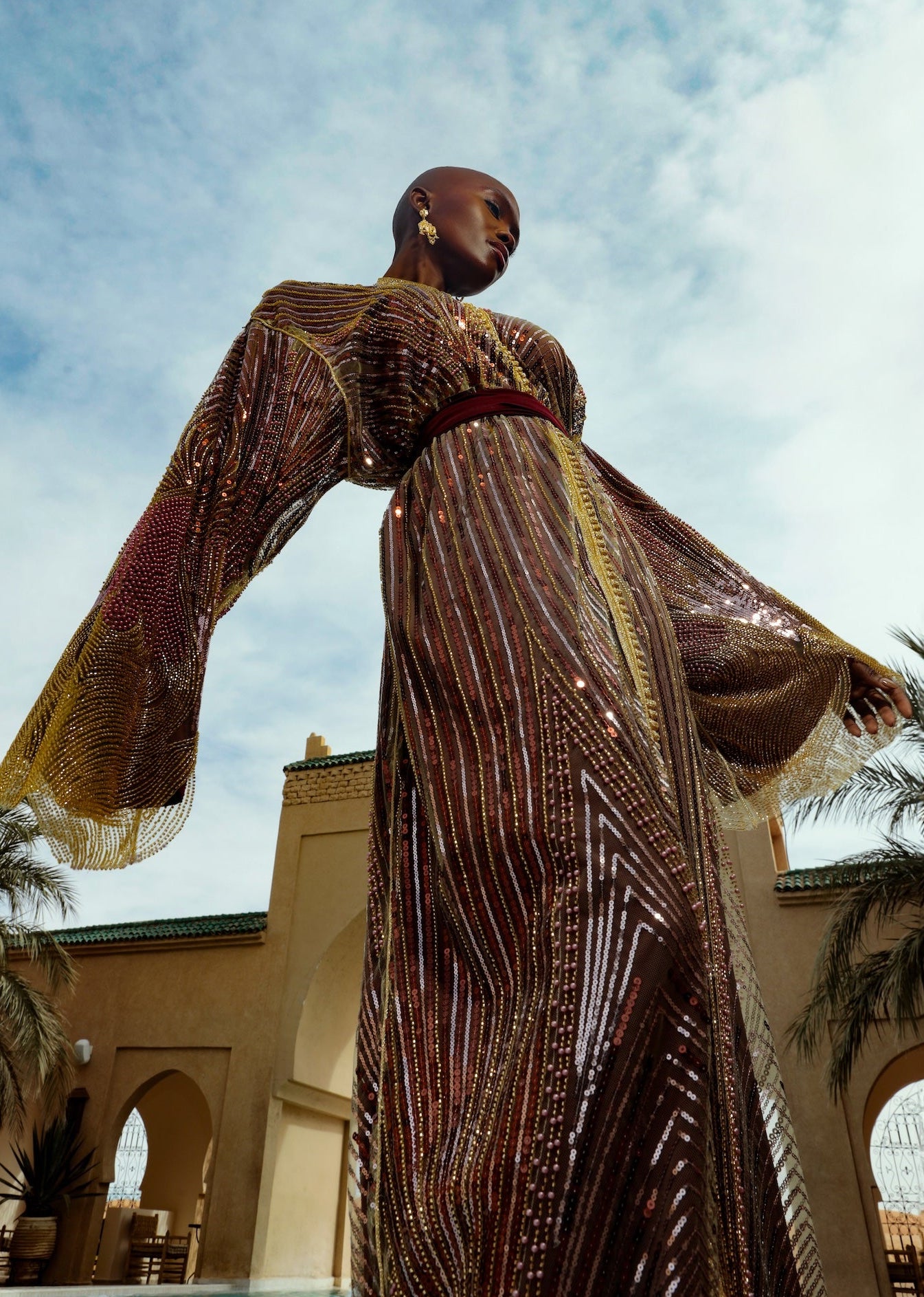 Caftan en tulle perlé doré et bordeaux porté en mouvement, effet fluide et raffiné.
