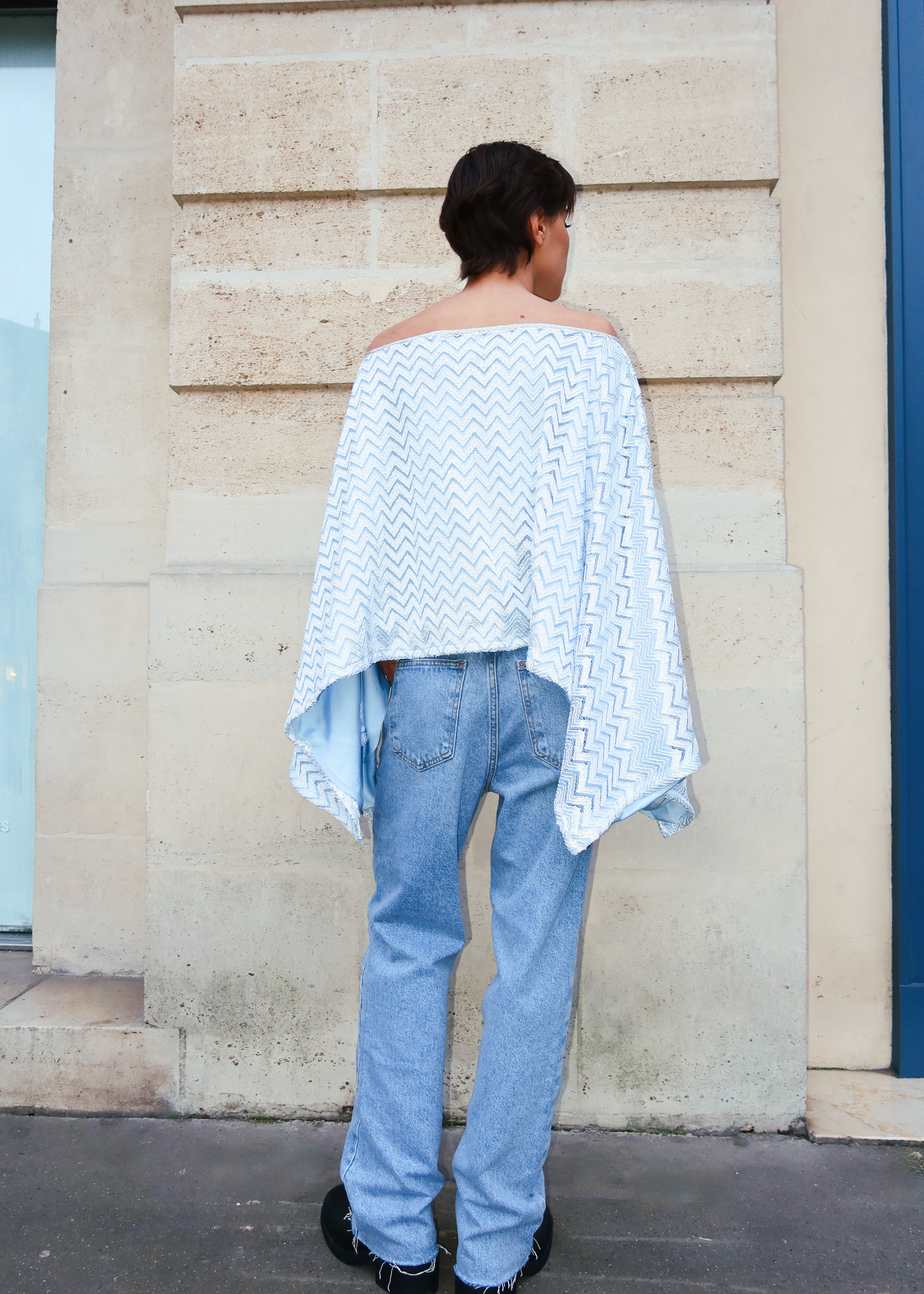 Vue de dos d’une cape en jersey bleu avec finitions zigzag et sfifa argentée raffinée