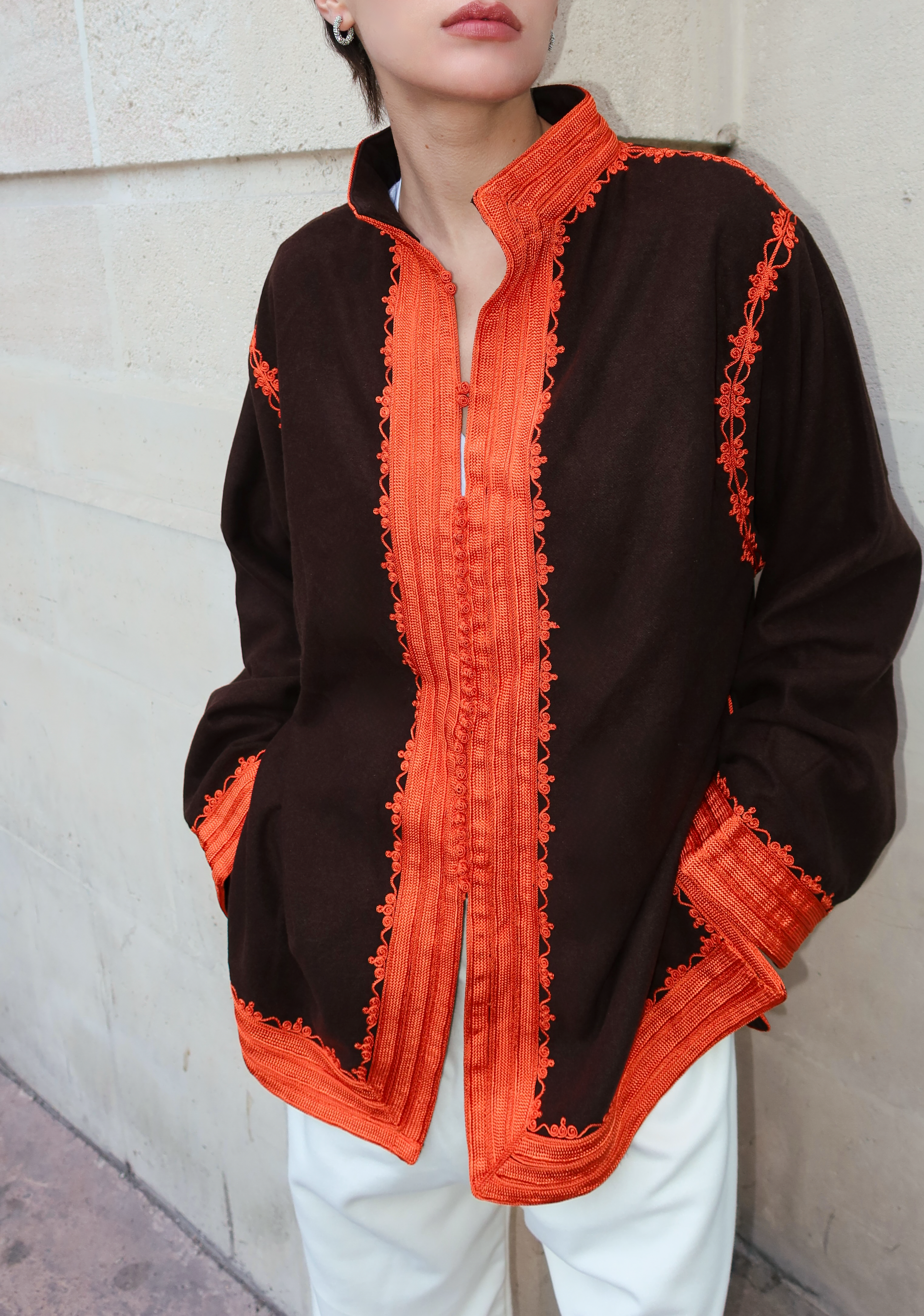 Gros plan sur les broderies orange artisanales d’une veste en cachemire marron