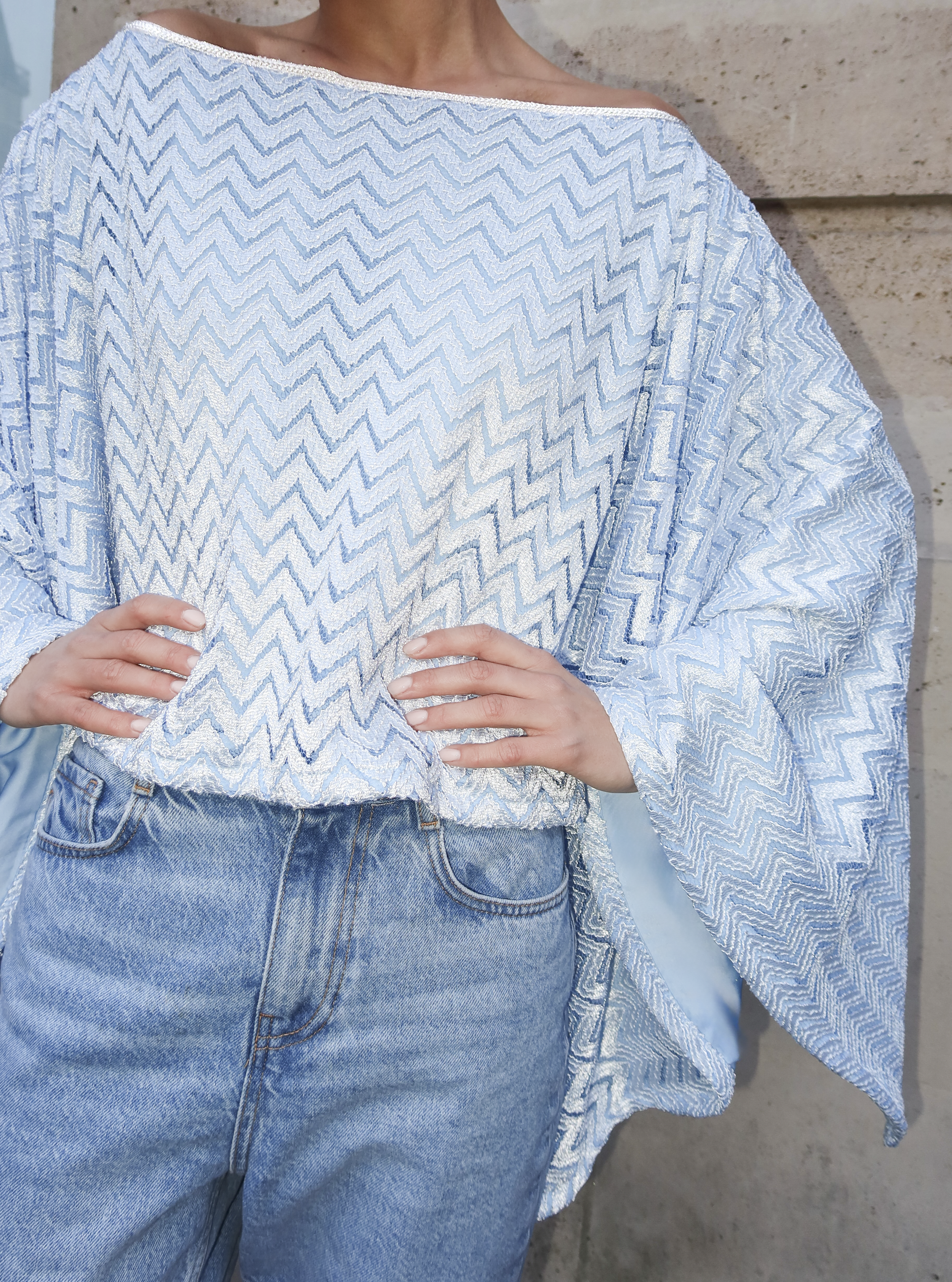 Gros plan sur la sfifa argentée et le motif zigzag d’une cape marocaine en jersey bleu