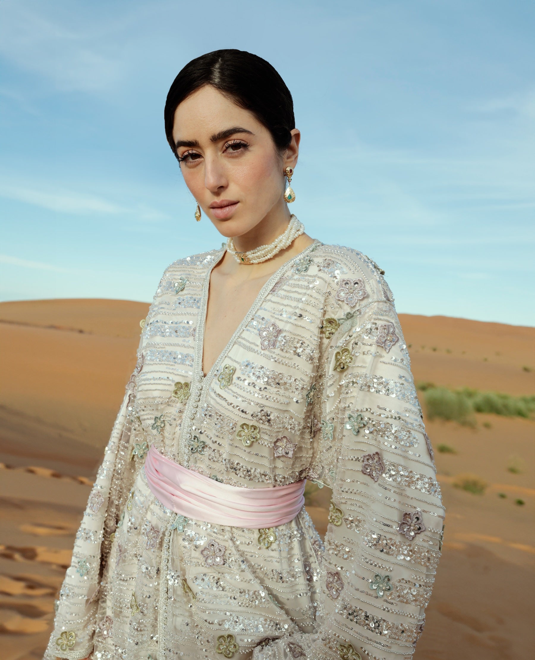 Gros plan sur les perles argentées formant des motifs floraux sur un caftan en tulle.