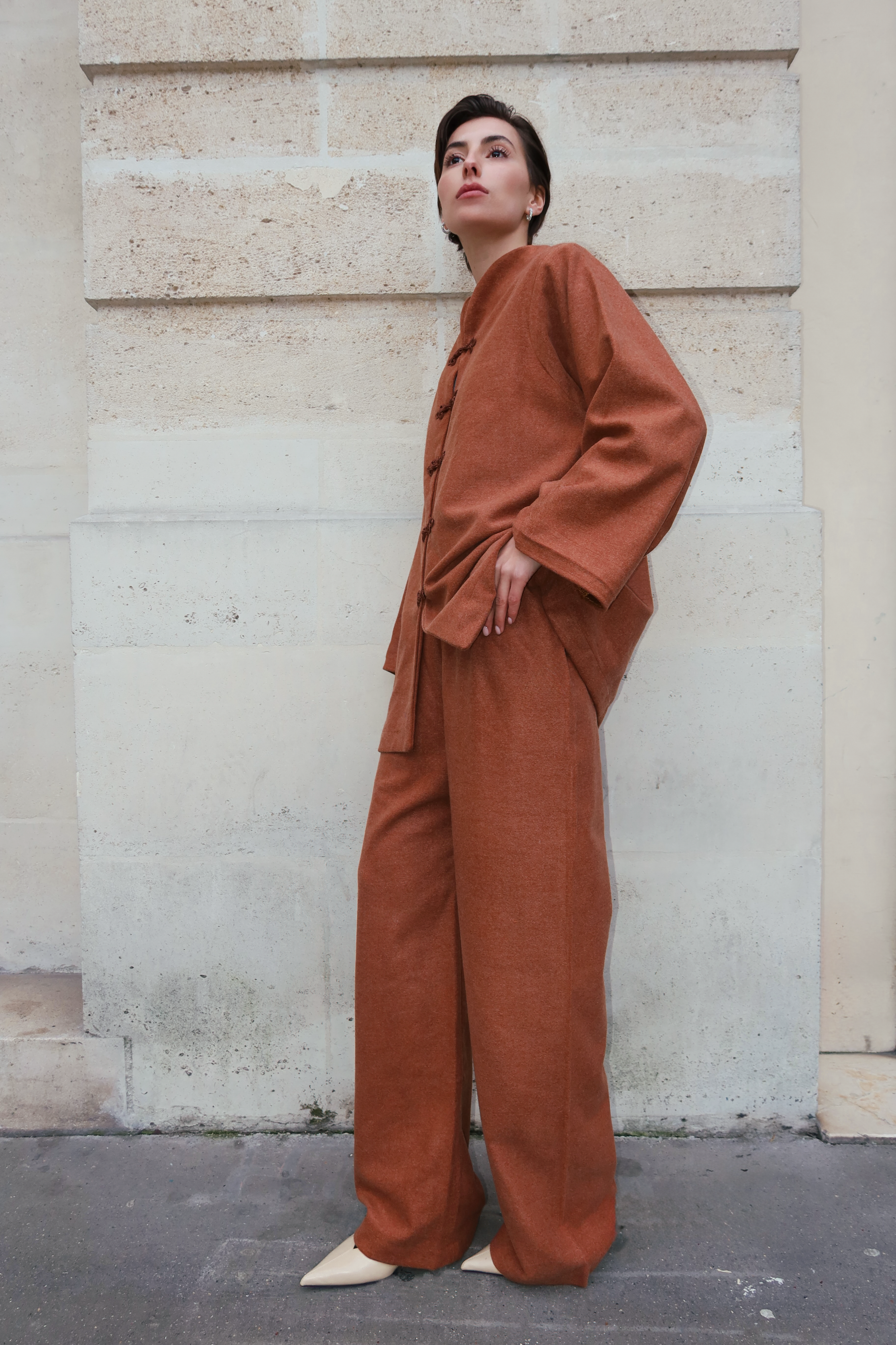Ensemble en cachemire marron vu de profil, mettant en valeur une coupe fluide et des boutons marocains
