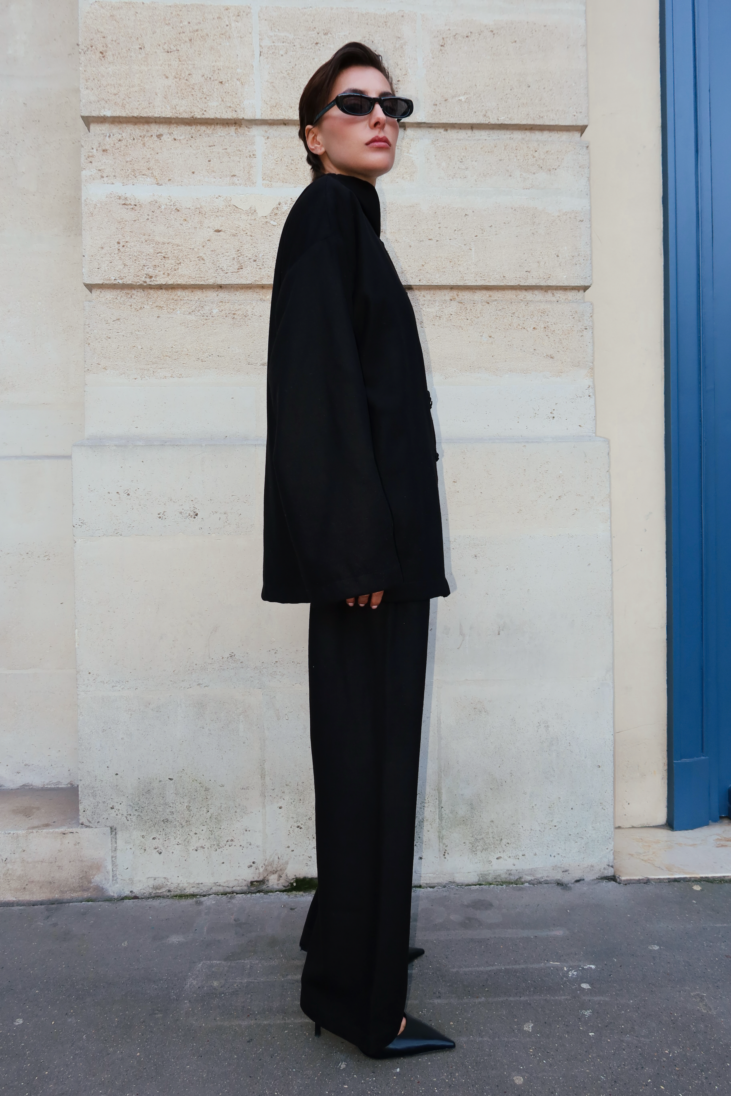 Ensemble en cachemire noir vu de profil, mettant en valeur une coupe fluide et des boutons marocains